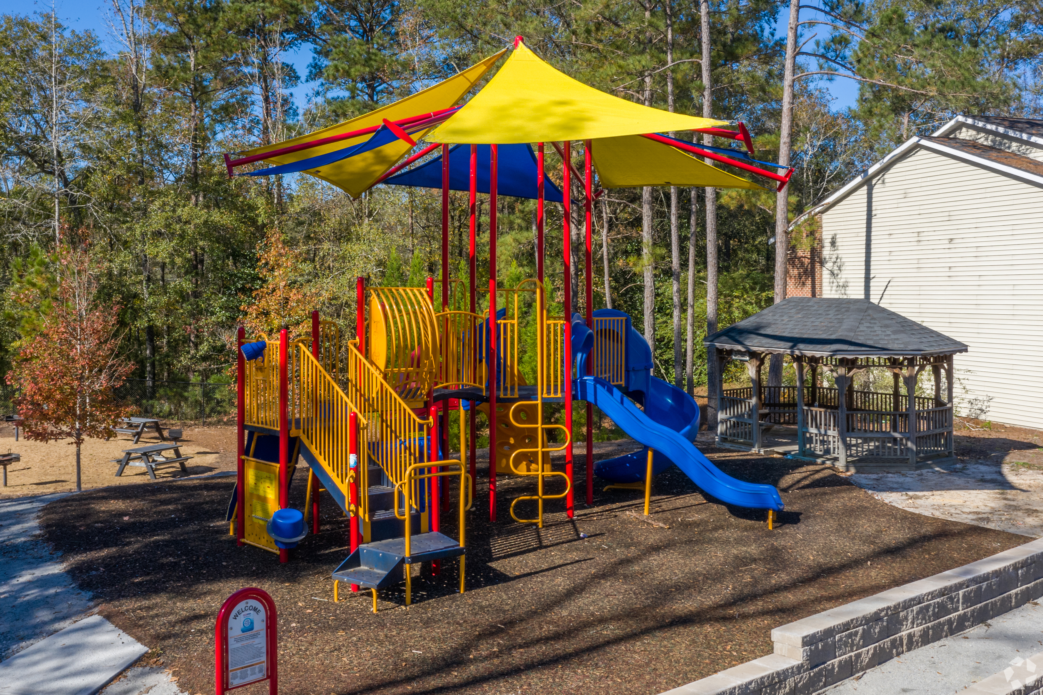Vibrant playground with colorful slides and climbing structures, set in a peaceful wooded area, perfect for family fun and outdoor enjoyment.