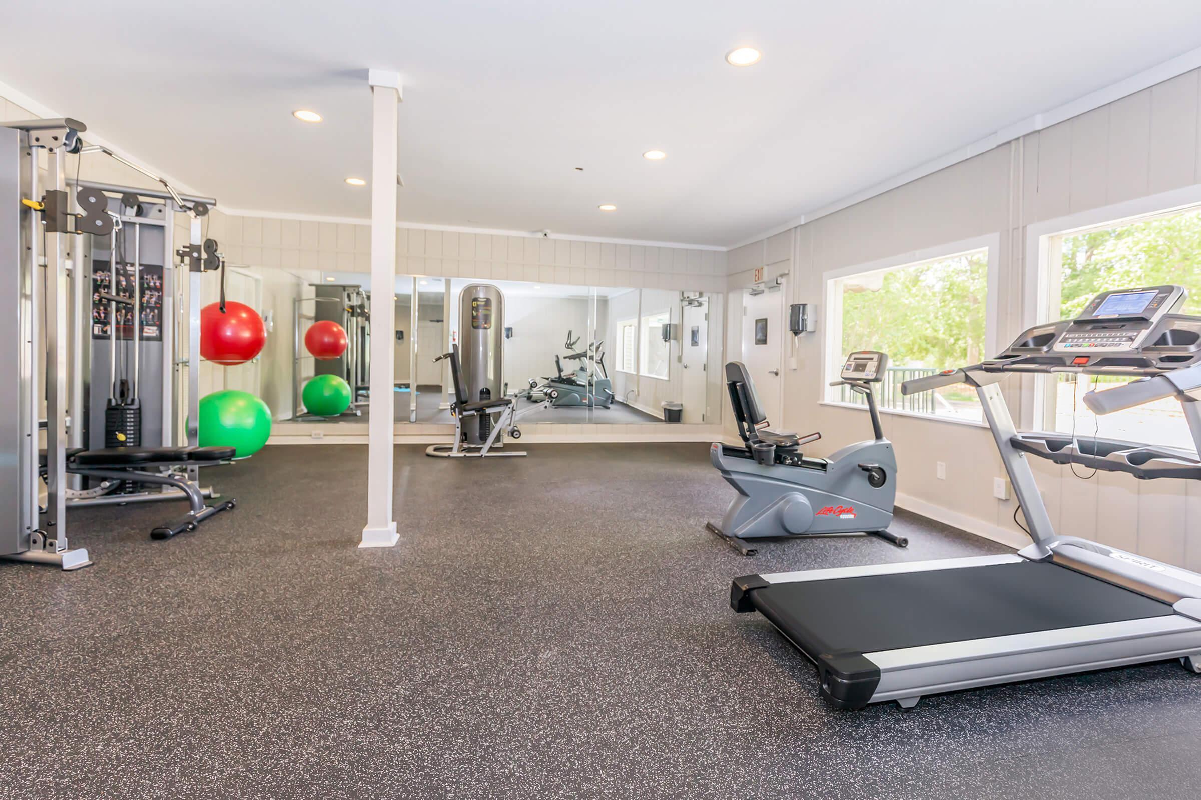 Bright and modern fitness center featuring state-of-the-art gym equipment, vibrant exercise balls, and large mirrors for an invigorating workout experience.