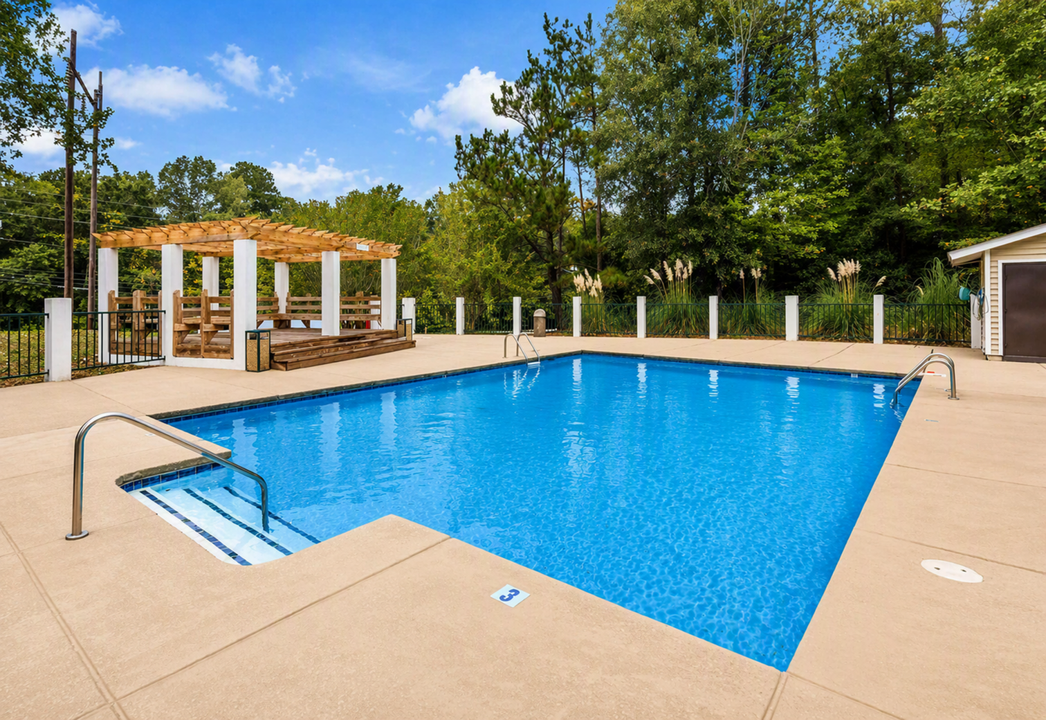 Inviting outdoor pool area with a serene atmosphere, surrounded by lush greenery and featuring a charming pergola for relaxation.