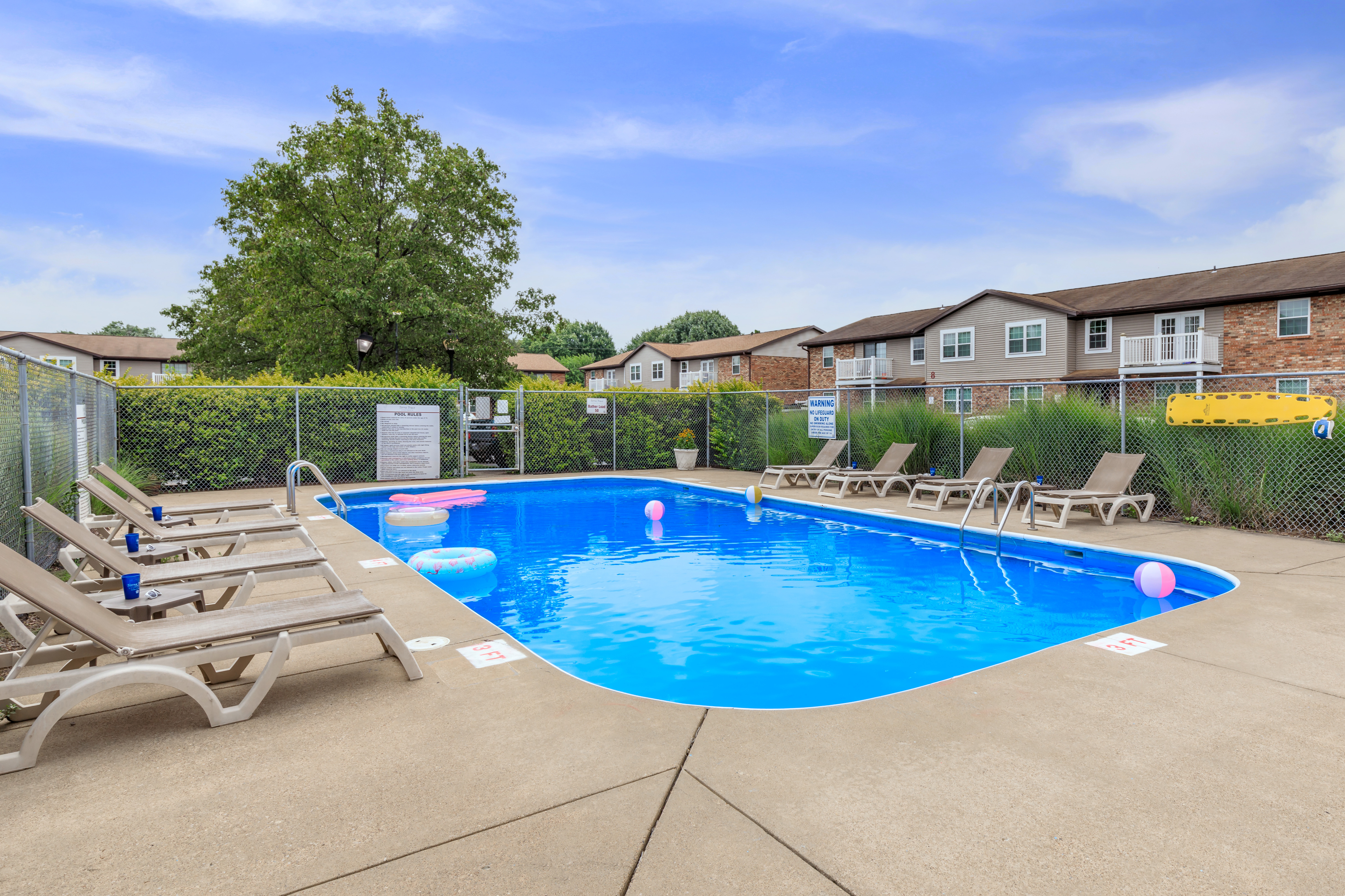 Inviting outdoor pool surrounded by comfortable lounge chairs and lush greenery, perfect for relaxation and summer fun.