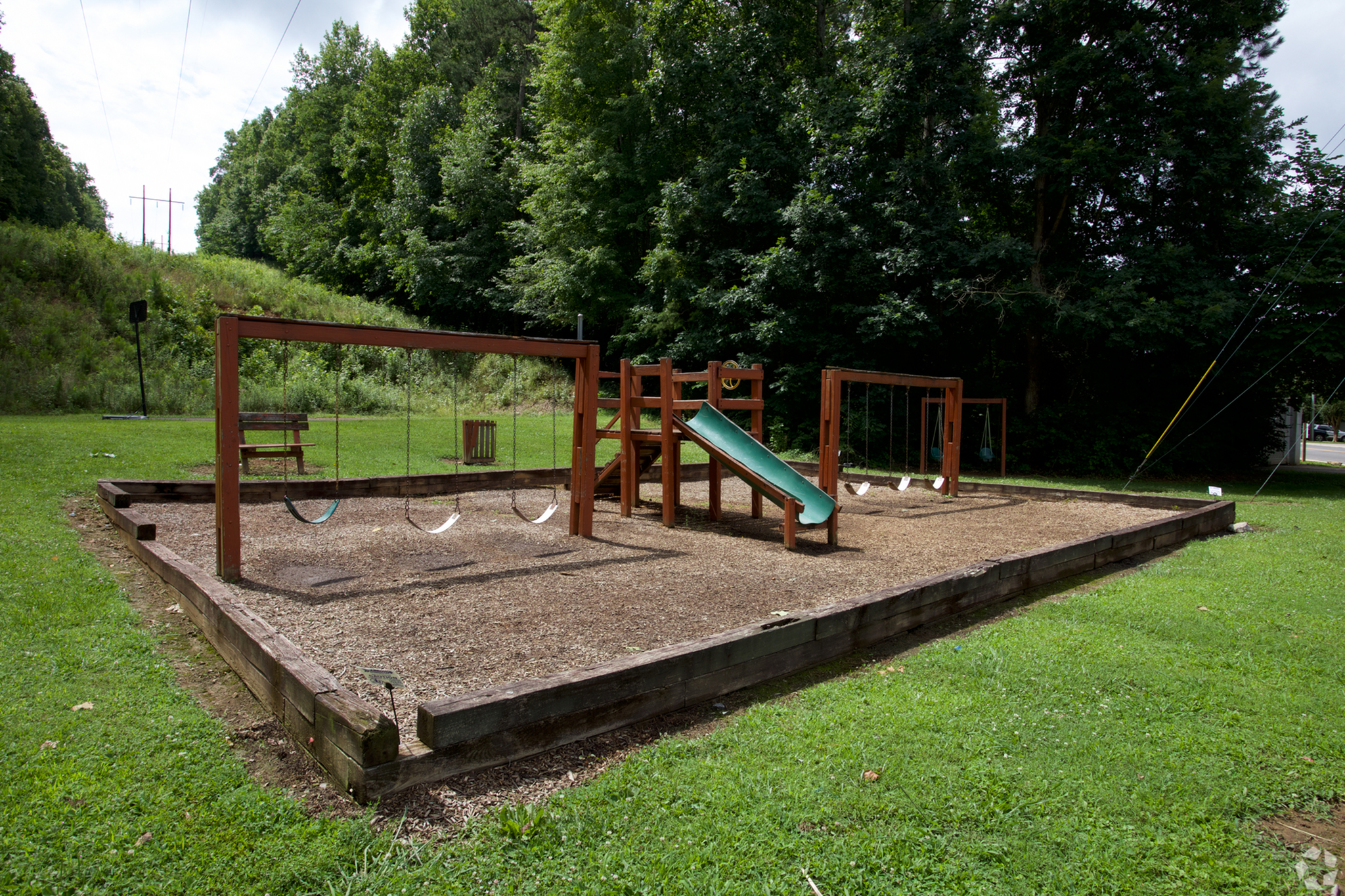 Inviting playground nestled in greenery featuring swings, a slide, and climbing structures, perfect for family fun.