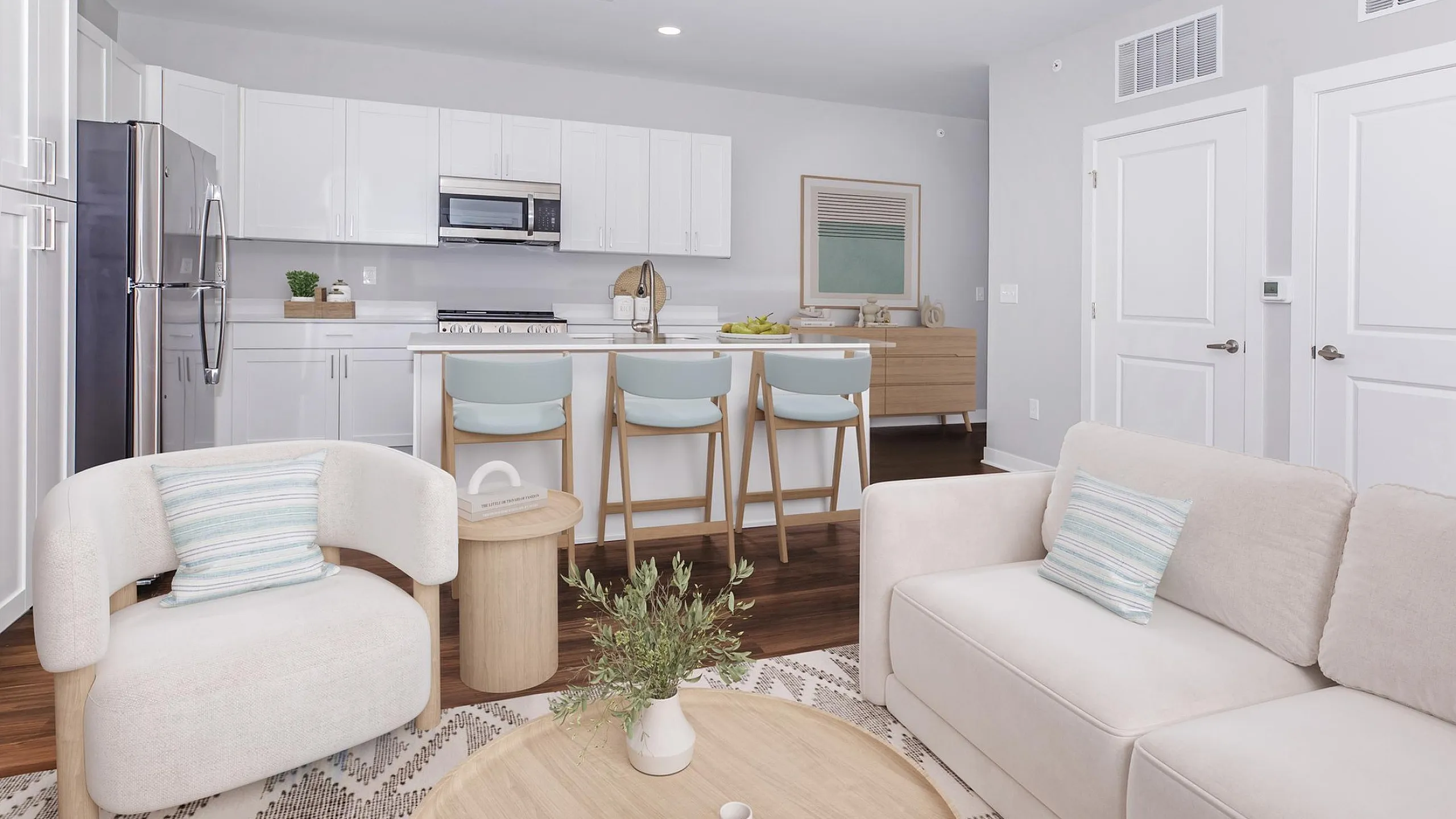 Contemporary open-concept kitchen and living area featuring sleek white cabinetry, stylish bar stools, and cozy modern seating.