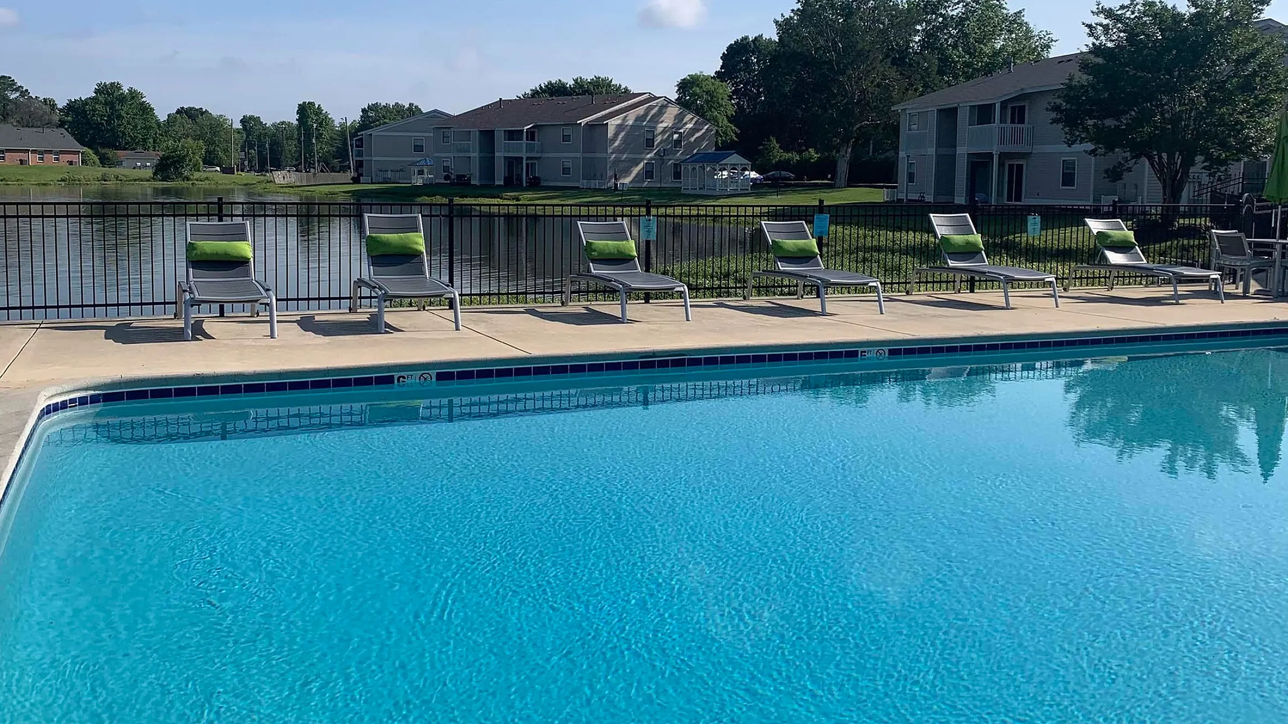 Inviting poolside view with stylish lounge chairs and scenic lakefront backdrop, perfect for relaxation.