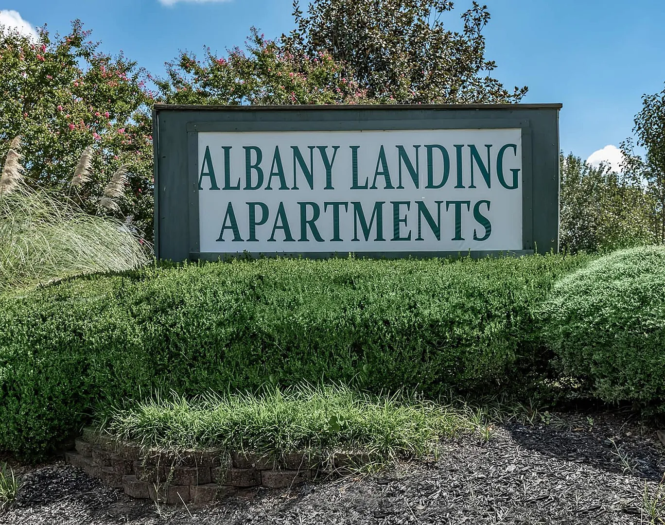 Inviting entrance sign for Albany Landing Apartments surrounded by lush greenery and vibrant landscaping.