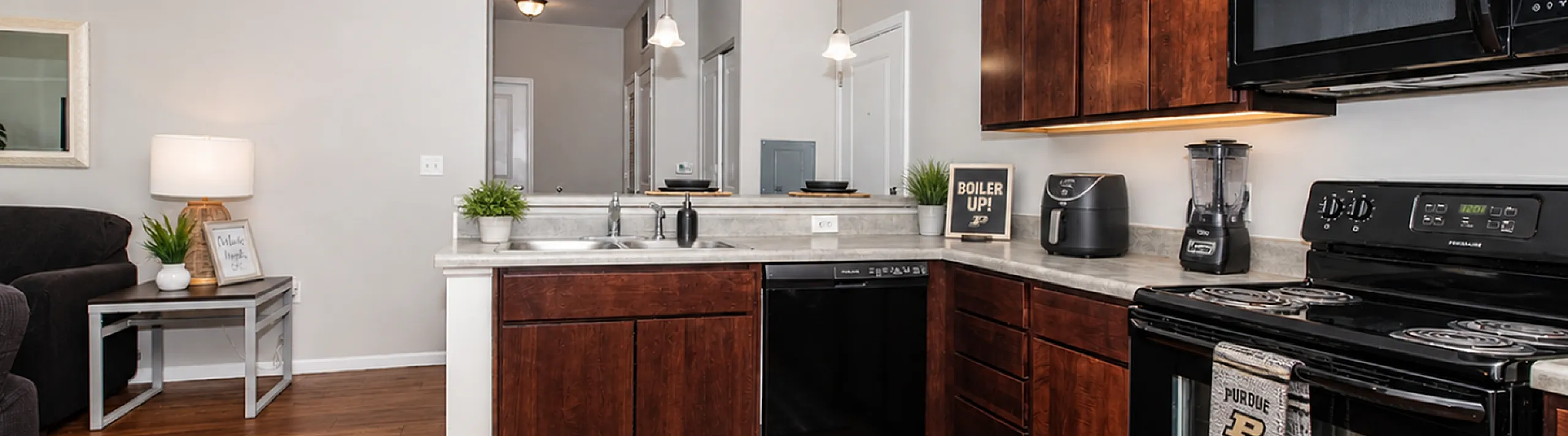 Modern kitchen with sleek appliances, rich wooden cabinetry, and open layout leading to a cozy living area.
