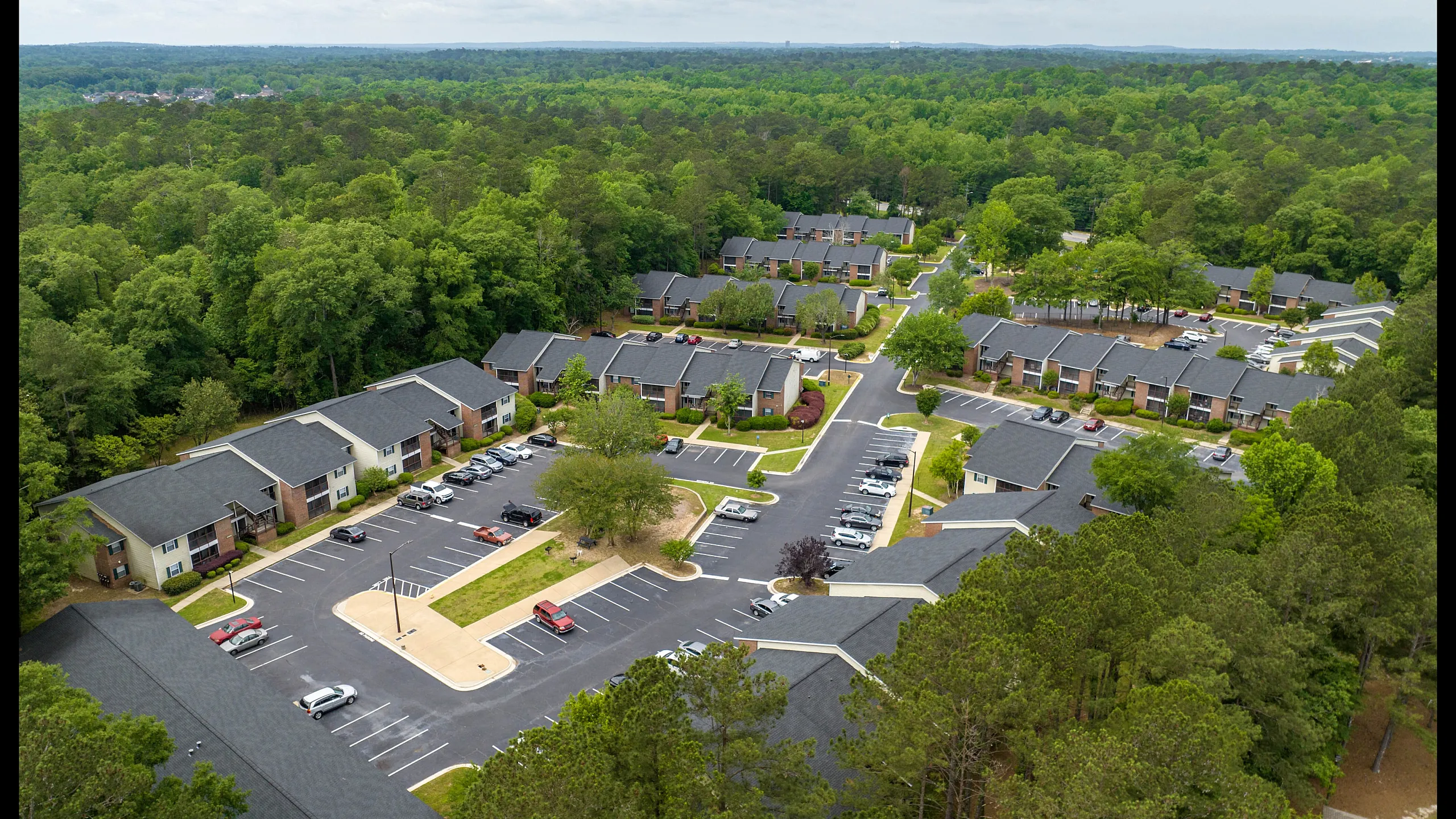 Charming apartment complex surrounded by lush greenery with ample parking and modern design.