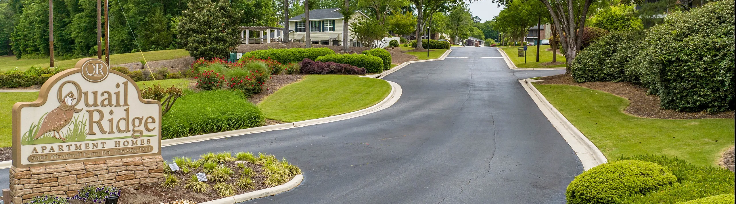 Inviting entryway to Quail Ridge Apartment Homes surrounded by lush greenery and well-maintained landscaping.