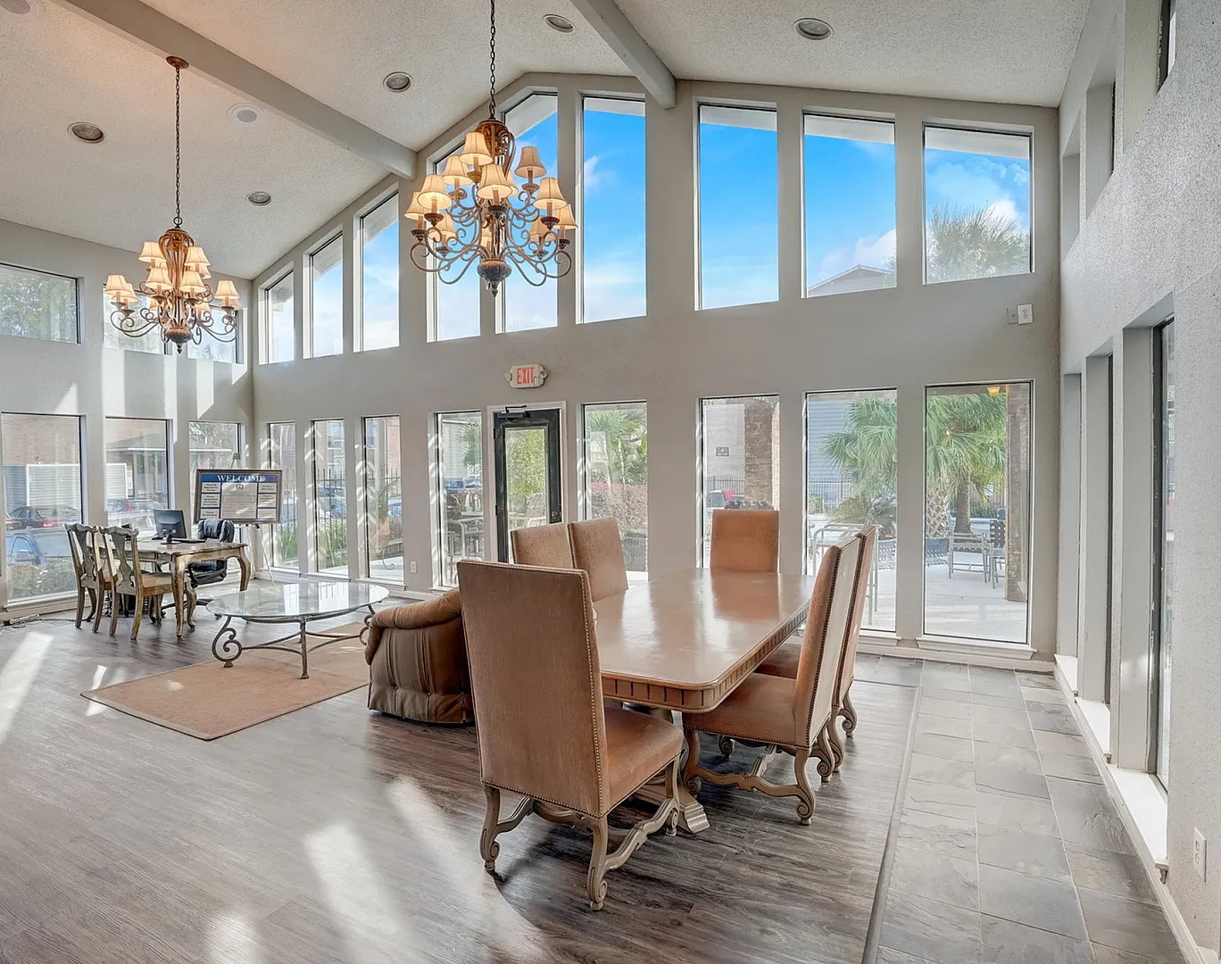 Bright and elegant dining room with vaulted ceilings, large windows, and stylish chandeliers, offering a spacious and inviting atmosphere.
