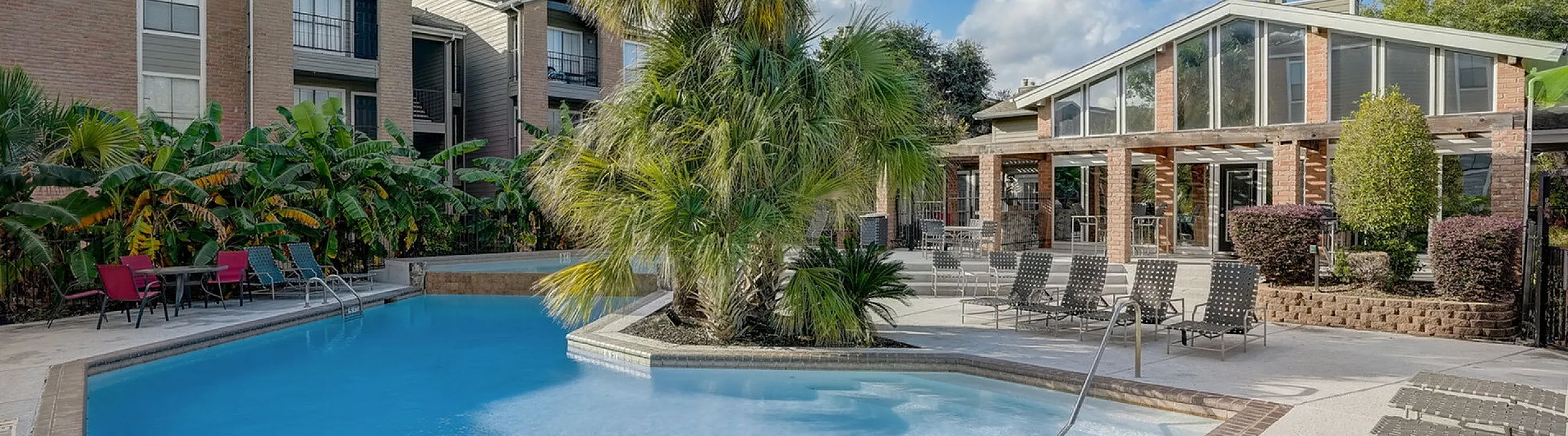 Inviting outdoor pool area surrounded by lush greenery and modern apartment buildings, perfect for relaxation and social gatherings.