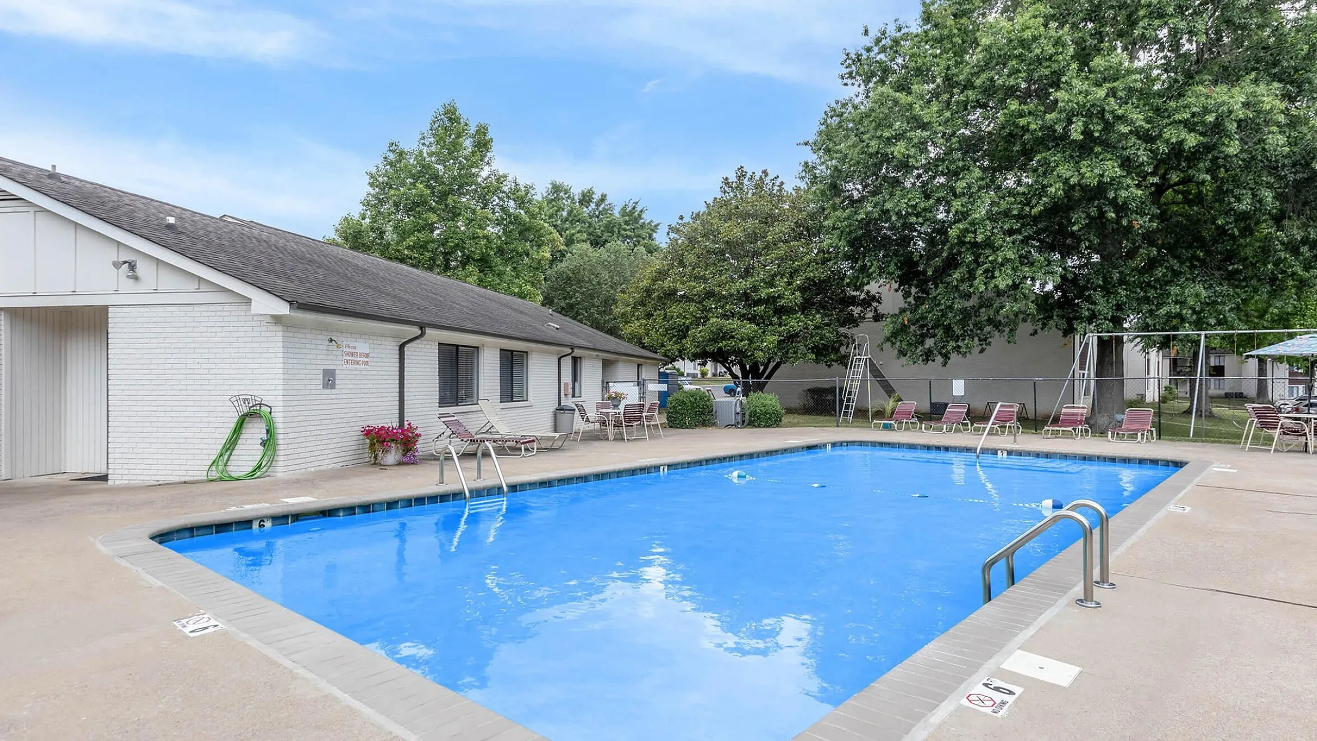 Inviting outdoor pool with comfortable lounge chairs and lush greenery, perfect for relaxation and enjoyment in a sunny setting.