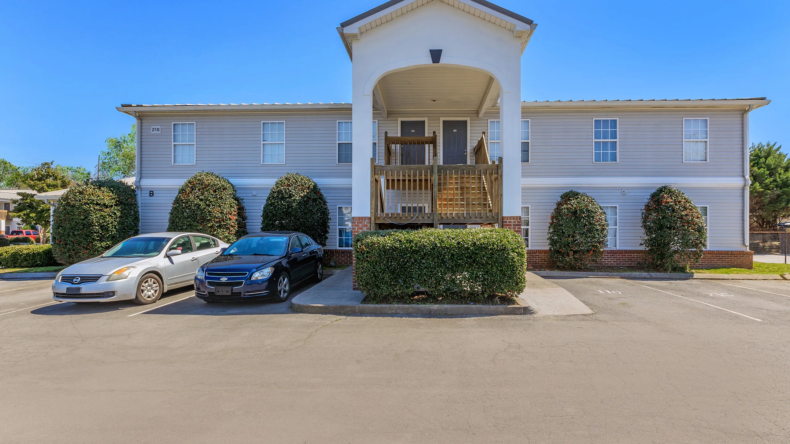 Inviting two-story apartment building with classic architecture, surrounded by lush greenery and convenient parking.