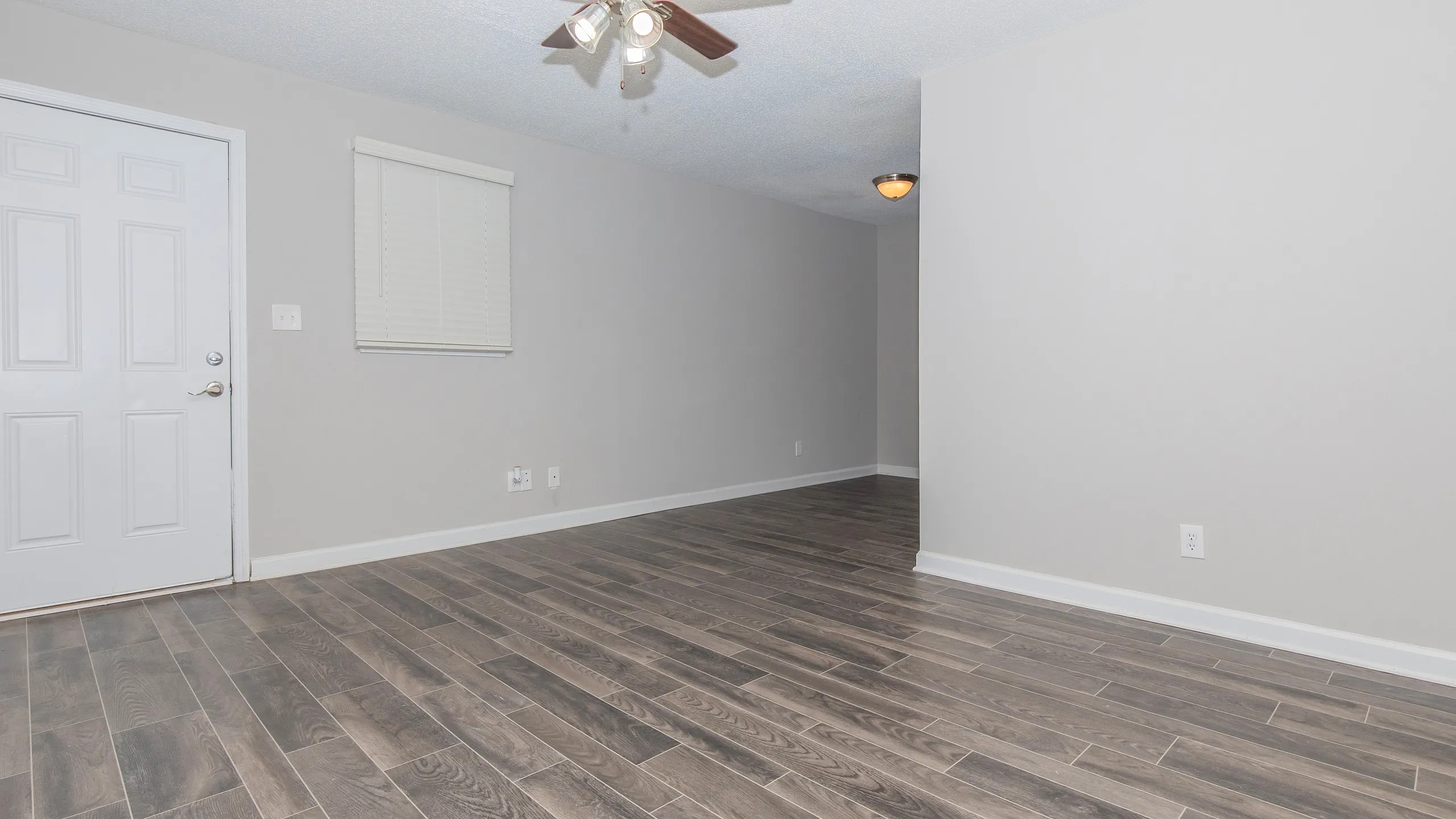 Modern apartment with elegant hardwood floors, ceiling fan, and ample natural light, perfect for stylish urban living.