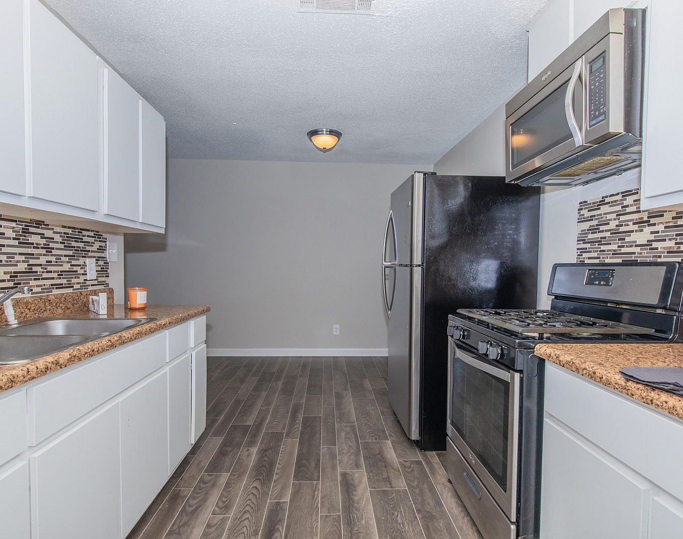 Modern kitchen with sleek stainless steel appliances, elegant brown granite countertops, and contemporary tile backsplash.