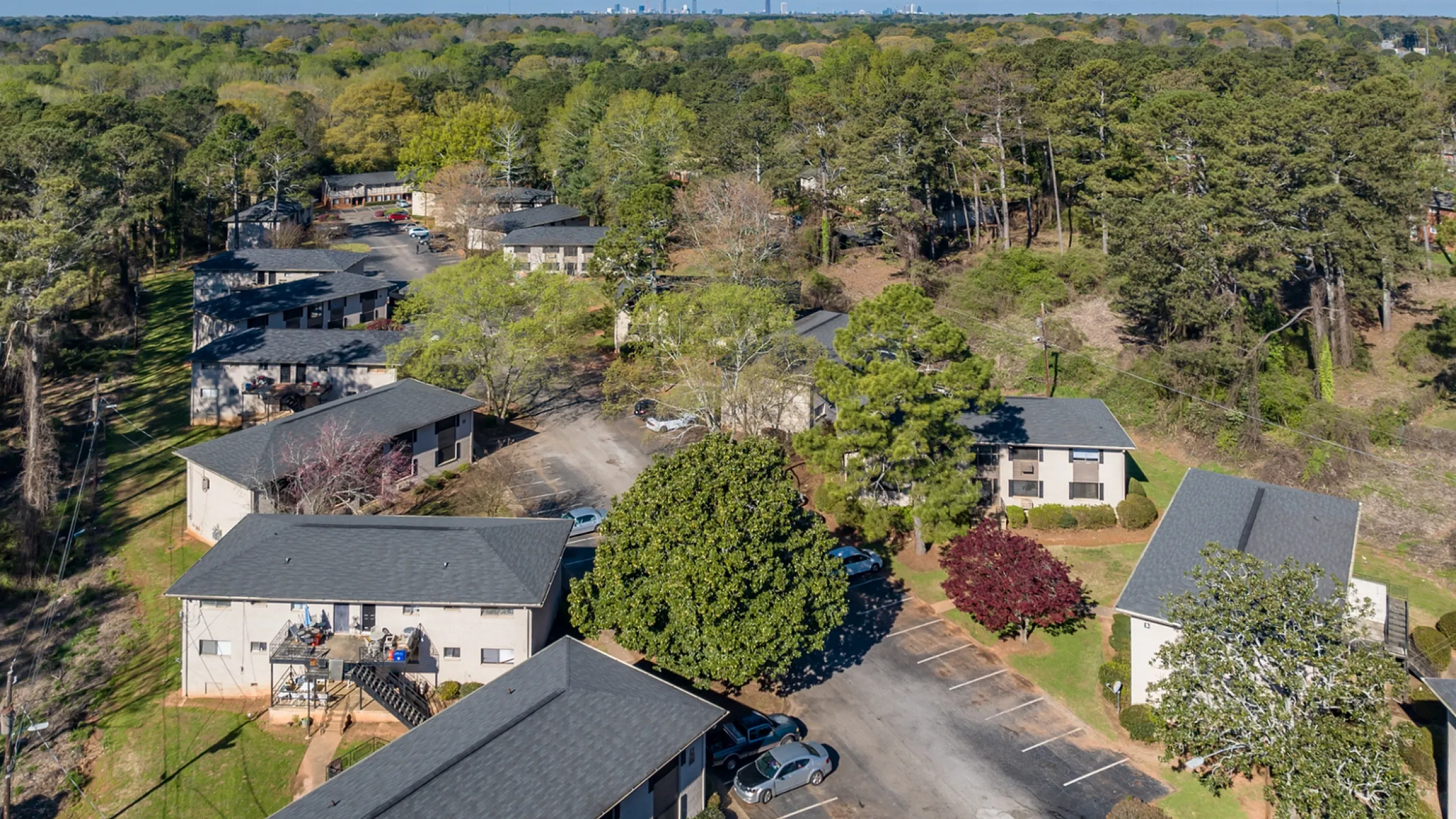 Aerial view of a serene apartment complex nestled among lush greenery and mature trees, offering a peaceful residential environment.