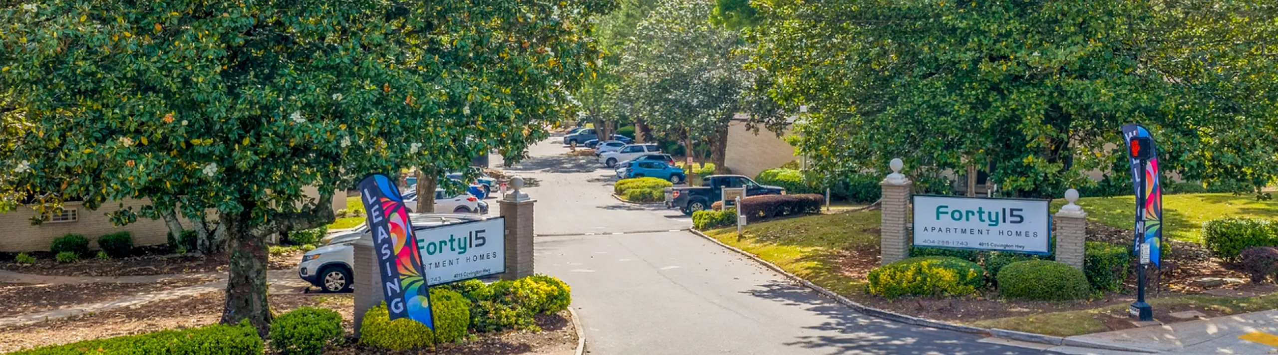 Welcoming entrance to Forty15 Apartment Homes, surrounded by lush greenery and vibrant landscaping.