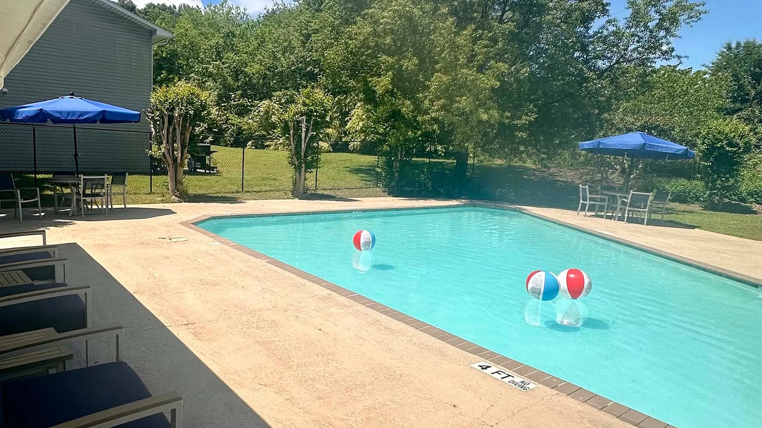 Inviting outdoor pool area featuring bright beach balls, comfortable lounge chairs, and shaded seating, offering a perfect spot for relaxation under the sun.