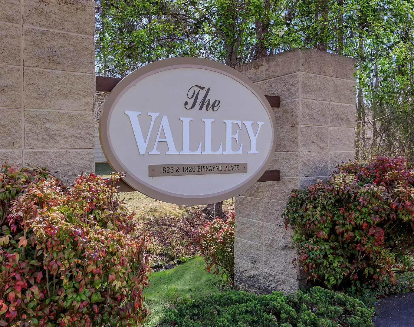Inviting entrance sign for 'The Valley' apartments, surrounded by lush greenery and vibrant foliage.