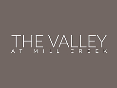 Elegant typography logo showcasing 'The Valley at Mill Creek' on a sophisticated taupe background.