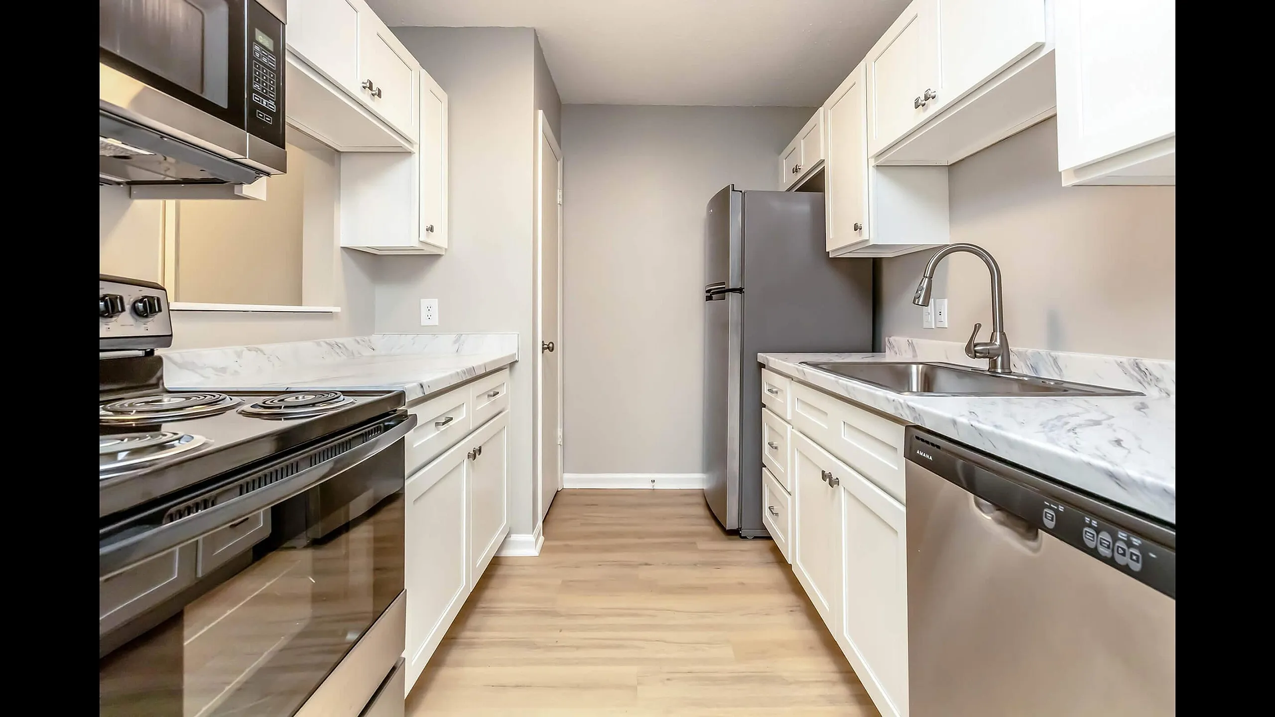 Sleek modern kitchen with stainless steel appliances, marble countertops, and elegant white cabinetry.