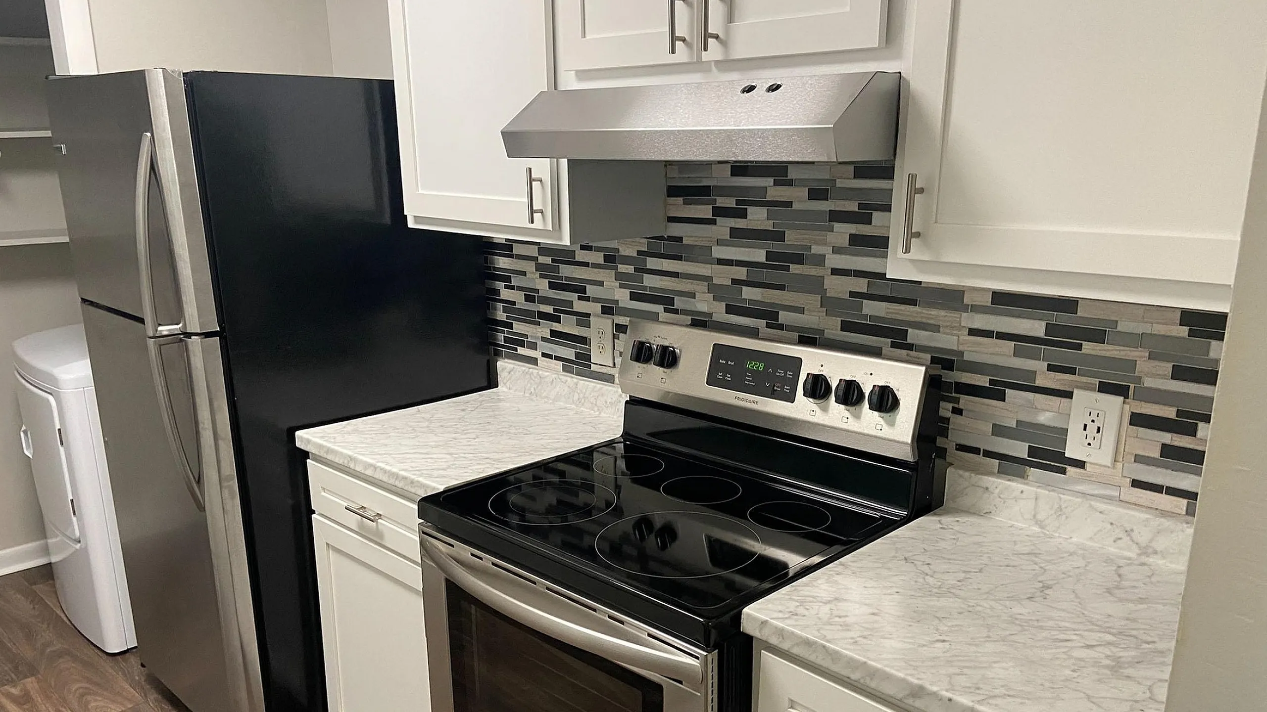 Modern kitchen with sleek appliances, stylish backsplash, and elegant countertops in a cozy apartment setting.