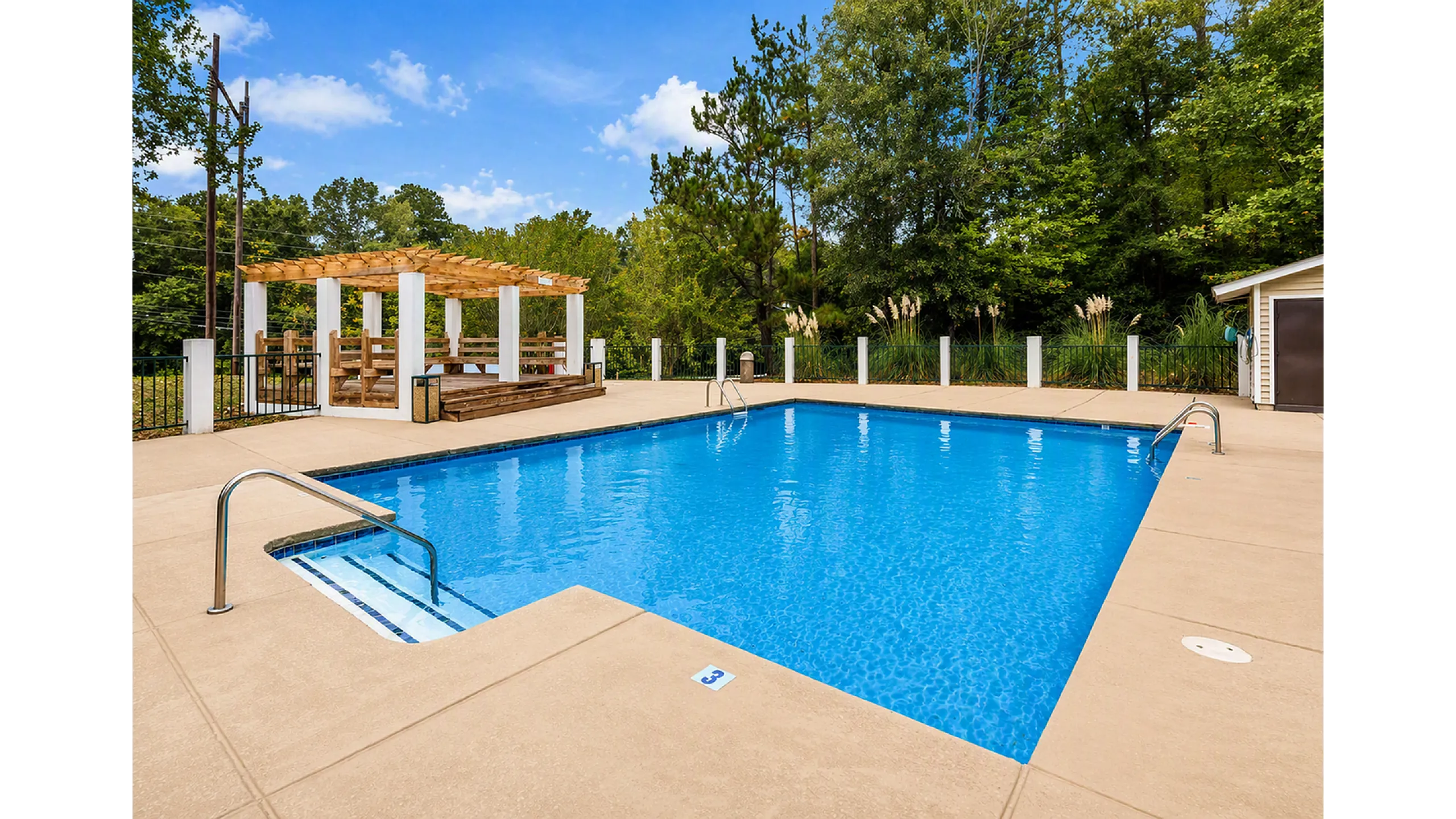Inviting outdoor pool with a serene pergola area surrounded by lush greenery, perfect for relaxation and leisure.