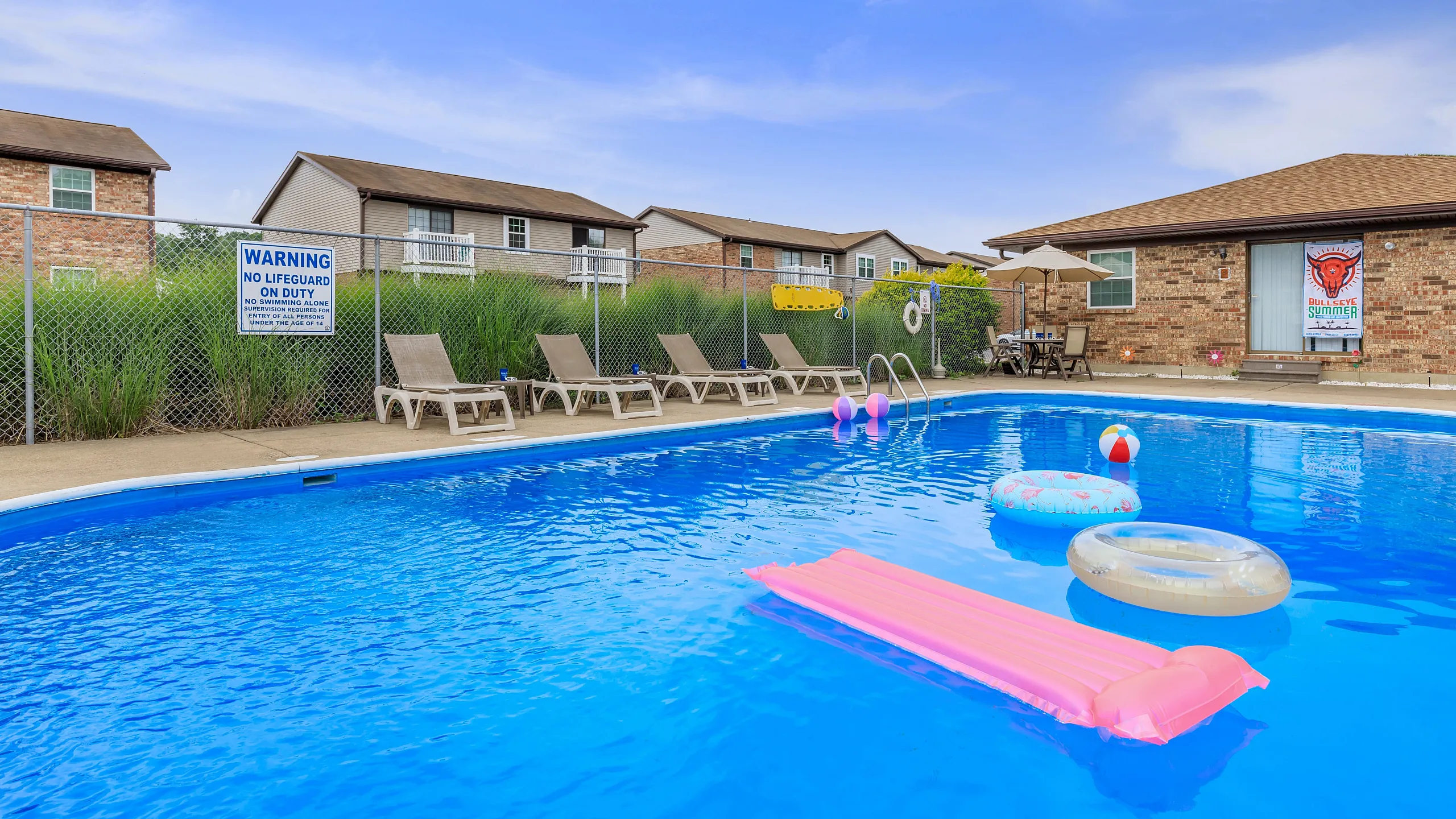 Inviting outdoor pool area with lounge chairs, colorful floaties, and a serene backdrop, perfect for a relaxing day in the sun.