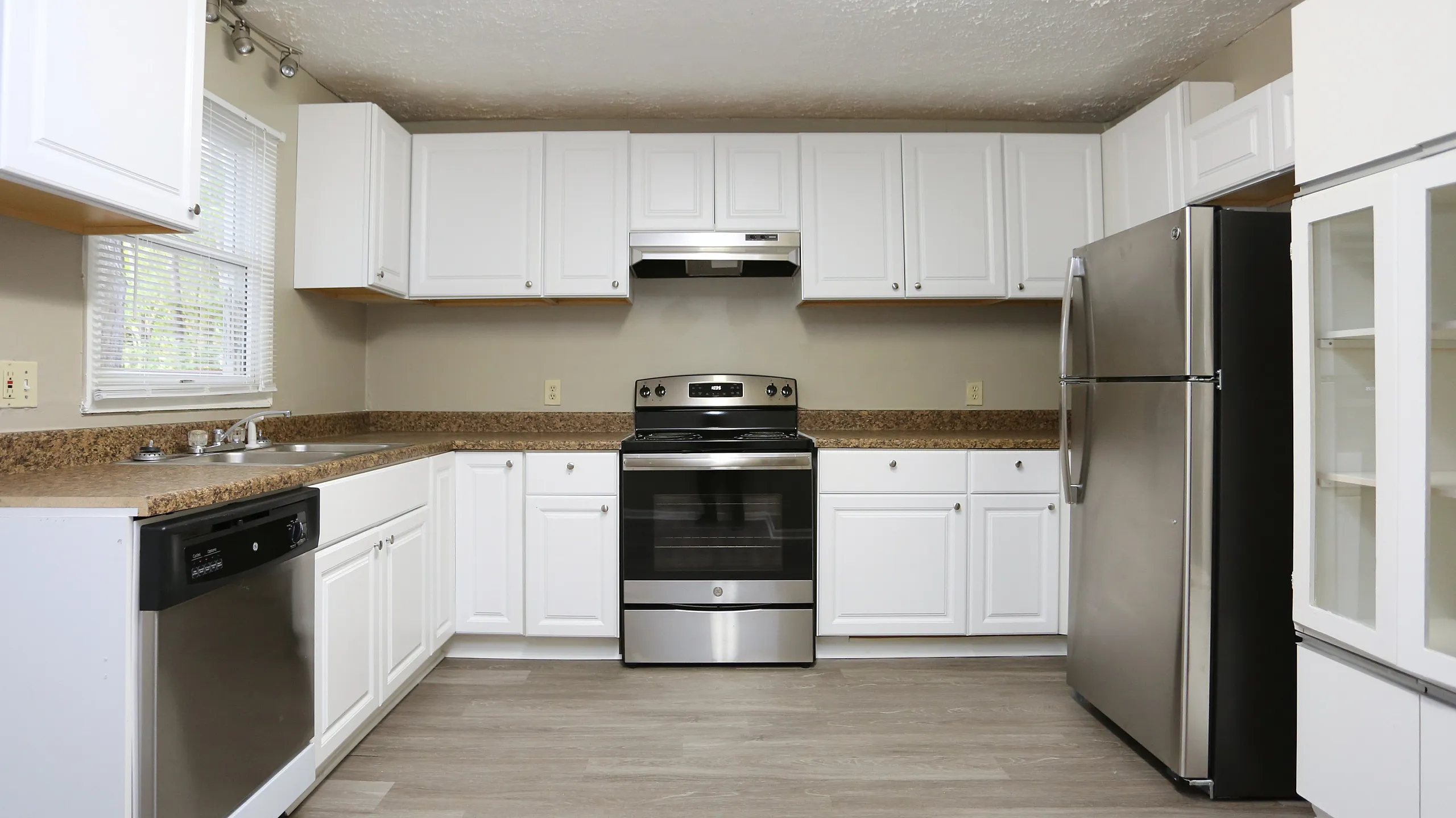 Modern kitchen with sleek stainless steel appliances, white cabinetry, and elegant wood flooring for a contemporary feel.