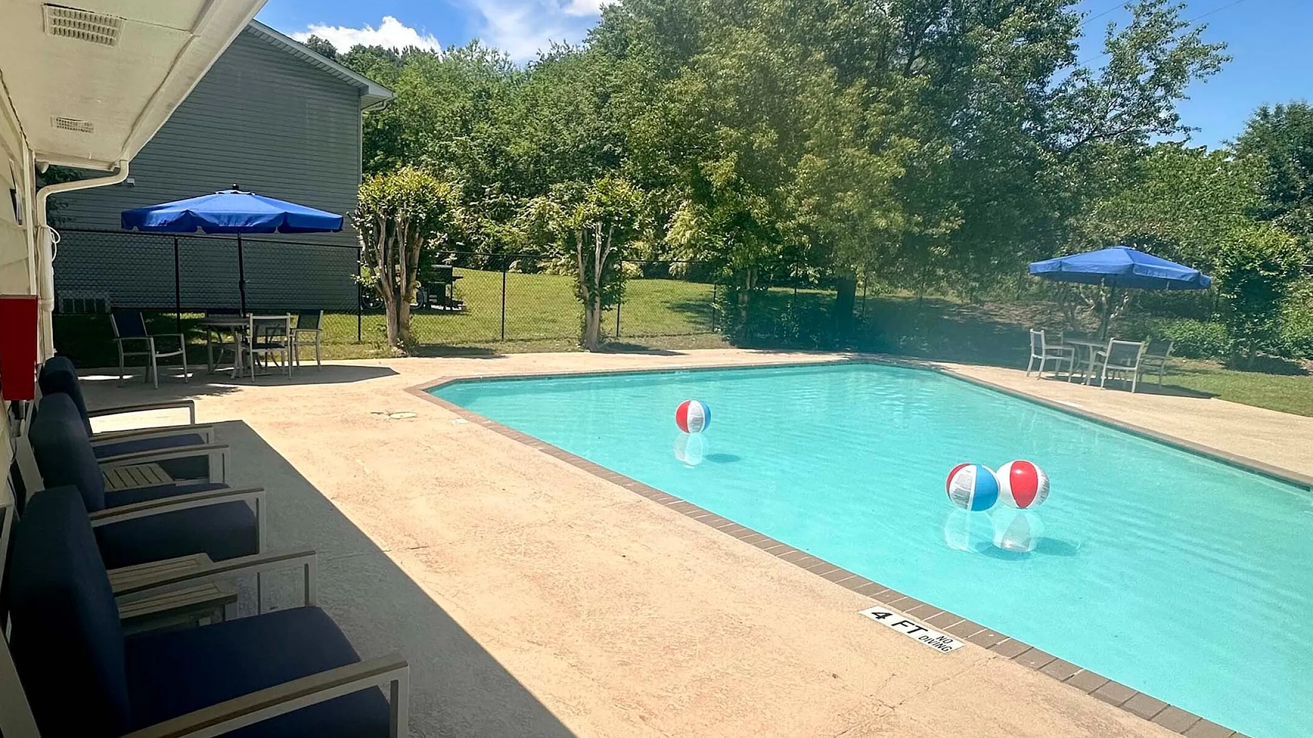 Inviting swimming pool area with sun loungers and blue umbrellas, perfect for relaxation and summer fun.