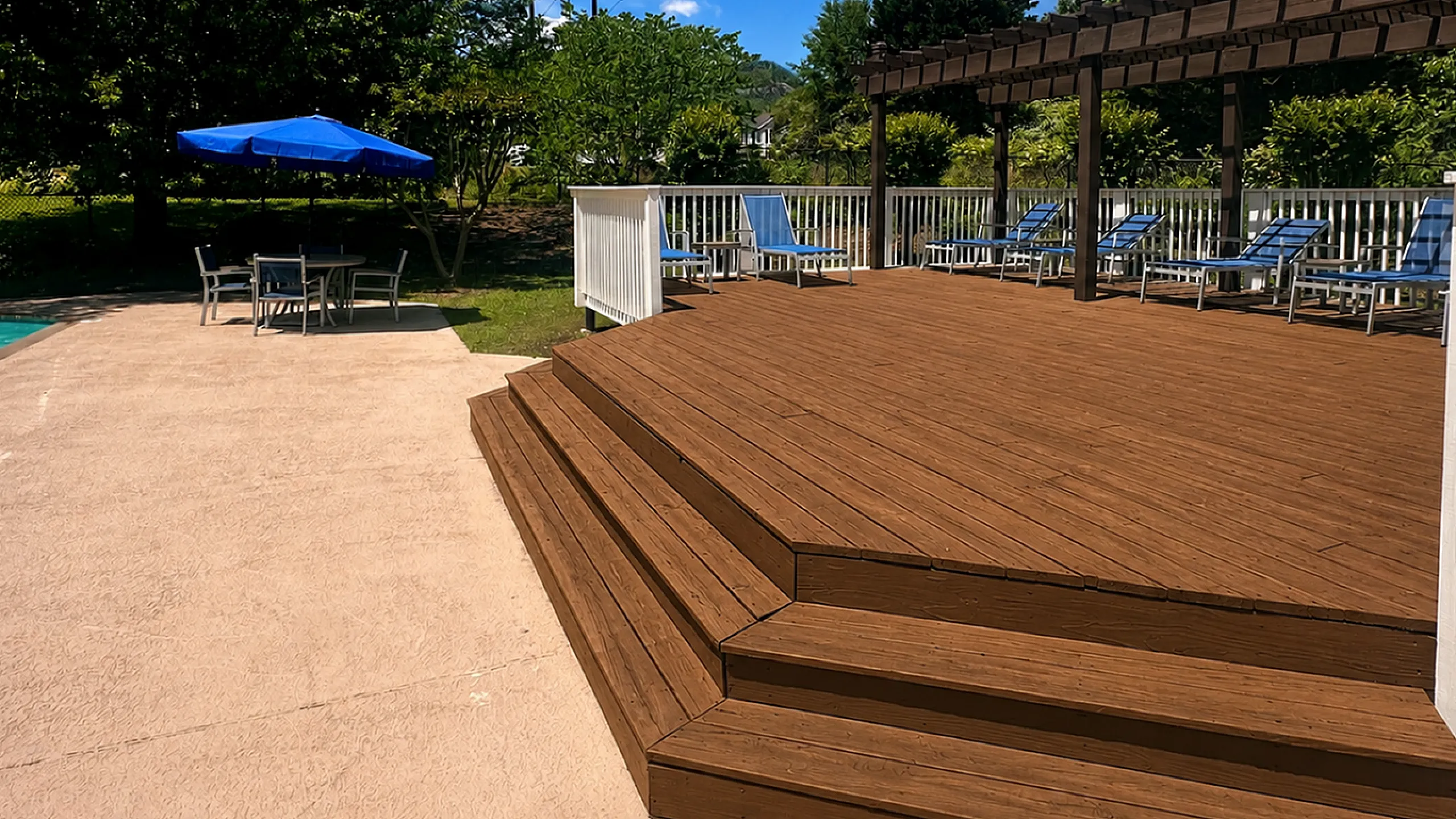 Charming outdoor deck with a pergola and poolside lounging area, surrounded by lush greenery, perfect for relaxation and entertaining.