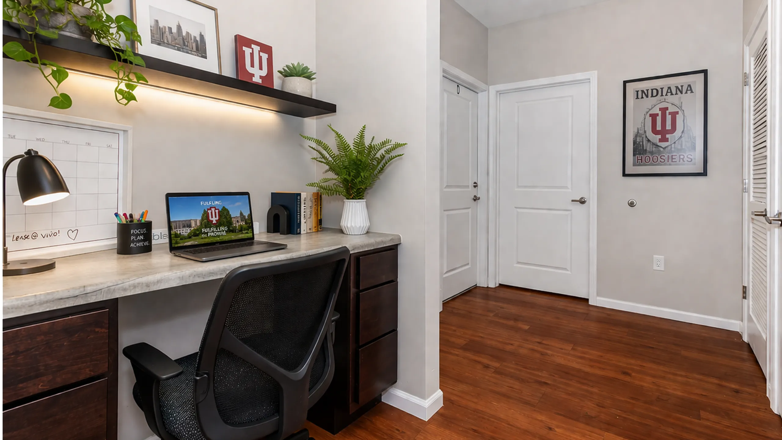 Cool IU study space with a modern desk setup, lush greenery, and warm wood flooring, perfect for productivity and inspiration.