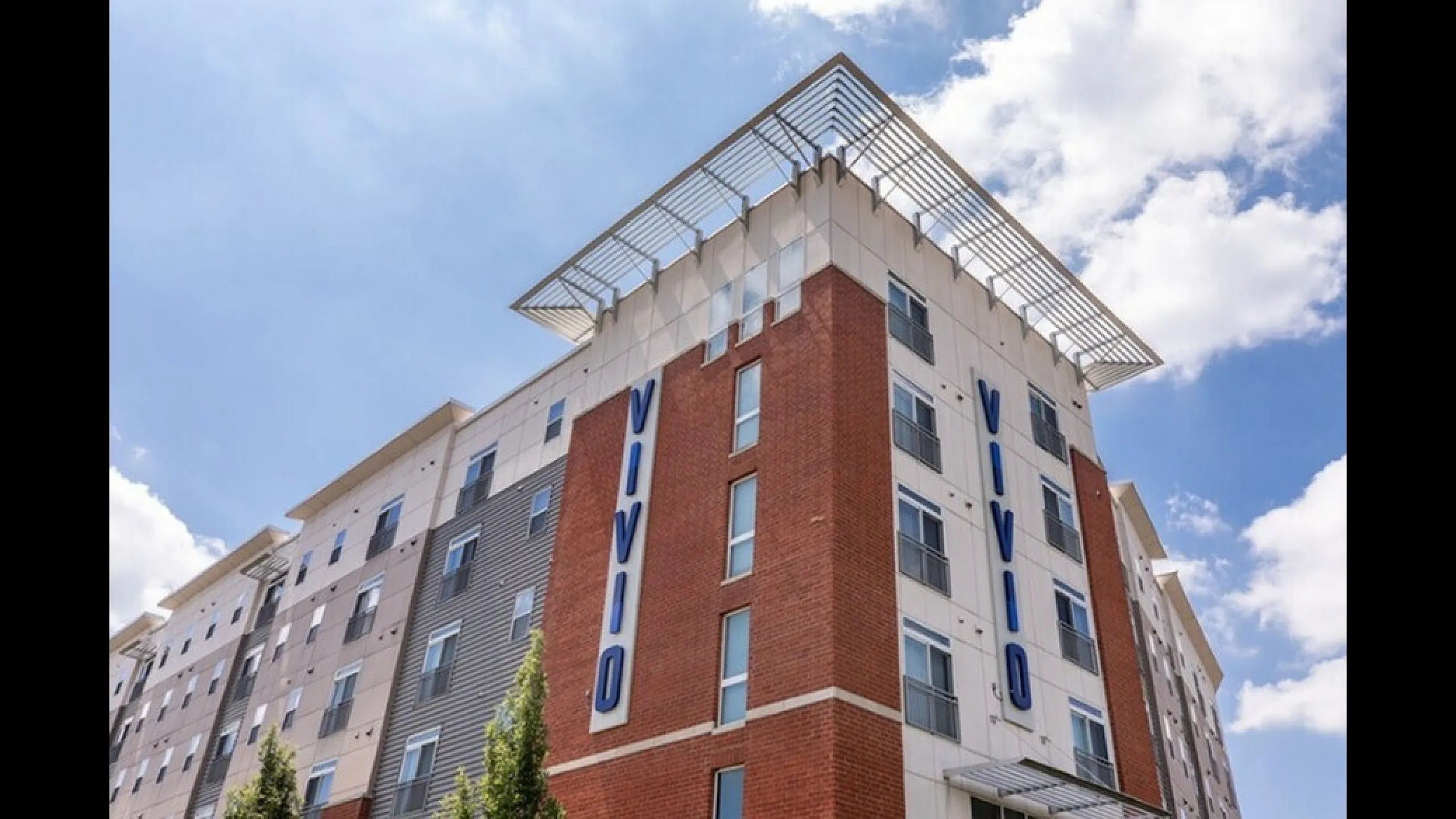 Modern apartment complex with stylish facade and vibrant brickwork, offering luxurious living spaces under a clear blue sky.