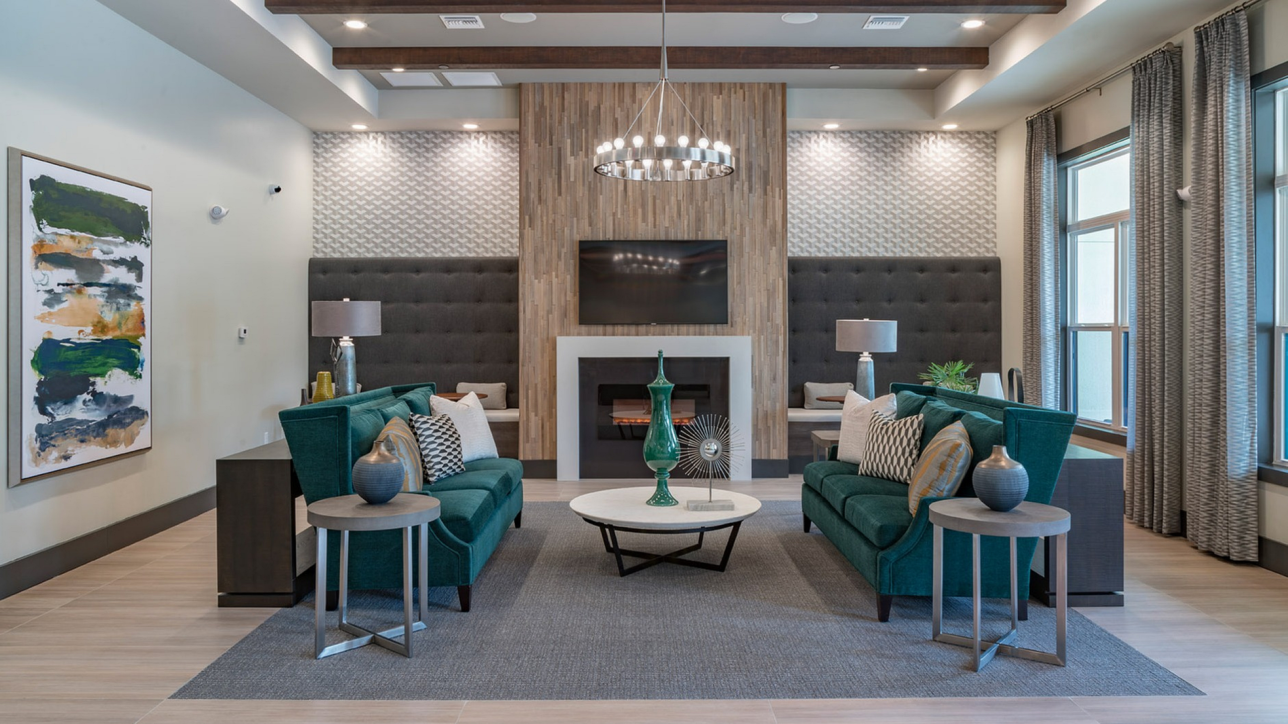 Luxurious contemporary living room with stylish teal sofas, elegant decor, and a modern fireplace centerpiece.