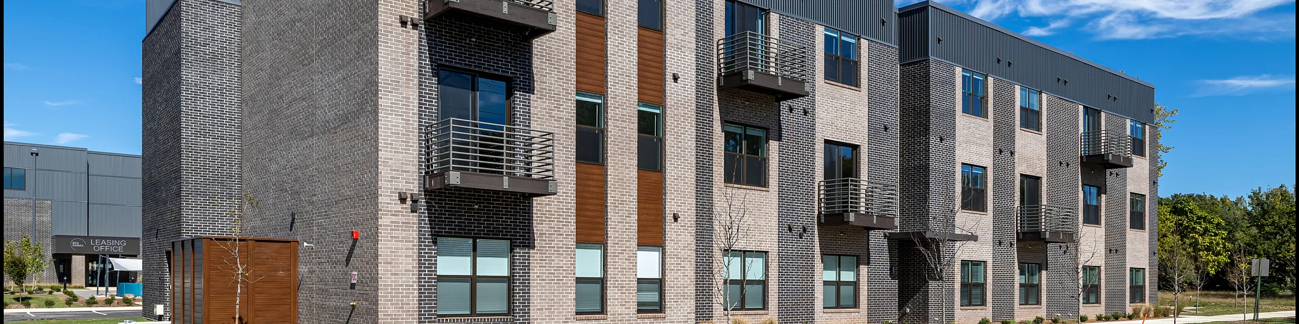 Modern three-story apartment building with stylish balconies and sleek brick facade in a vibrant neighborhood.