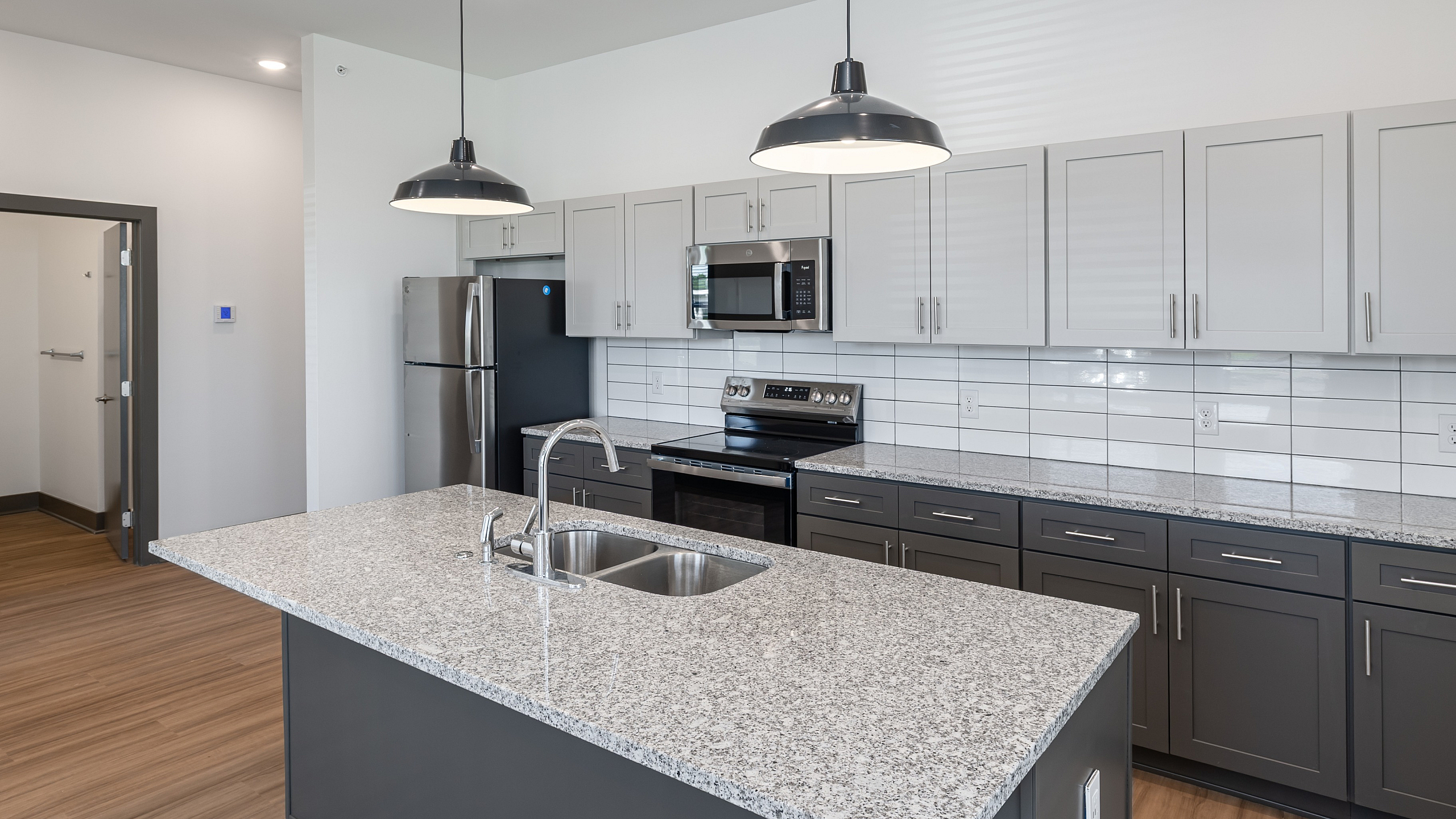Modern kitchen with sleek granite countertops, stainless steel appliances, and elegant cabinetry, illuminated by contemporary pendant lighting.