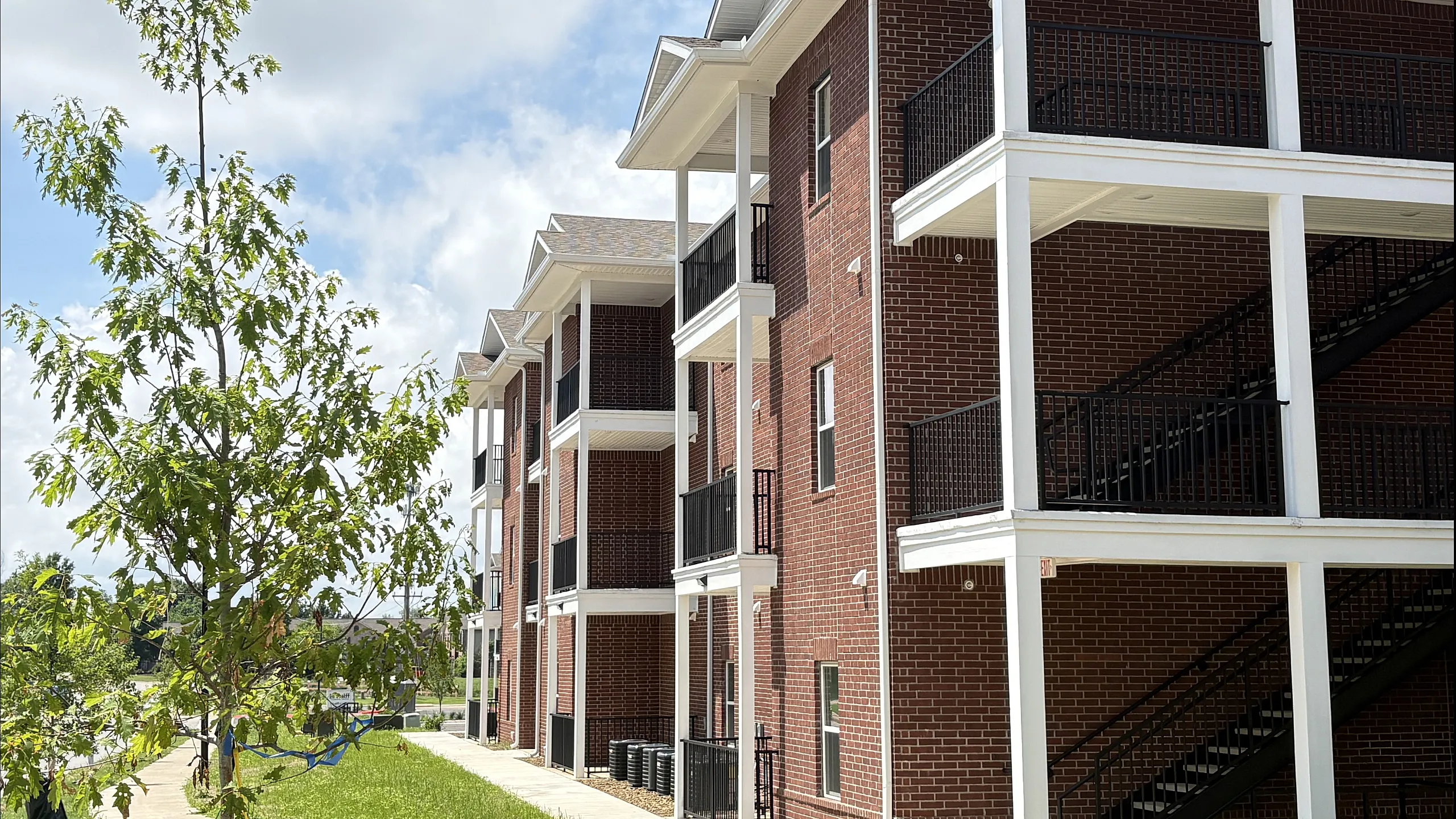 Charming red-brick apartment complex with spacious balconies and lush greenery, ideal for modern living.