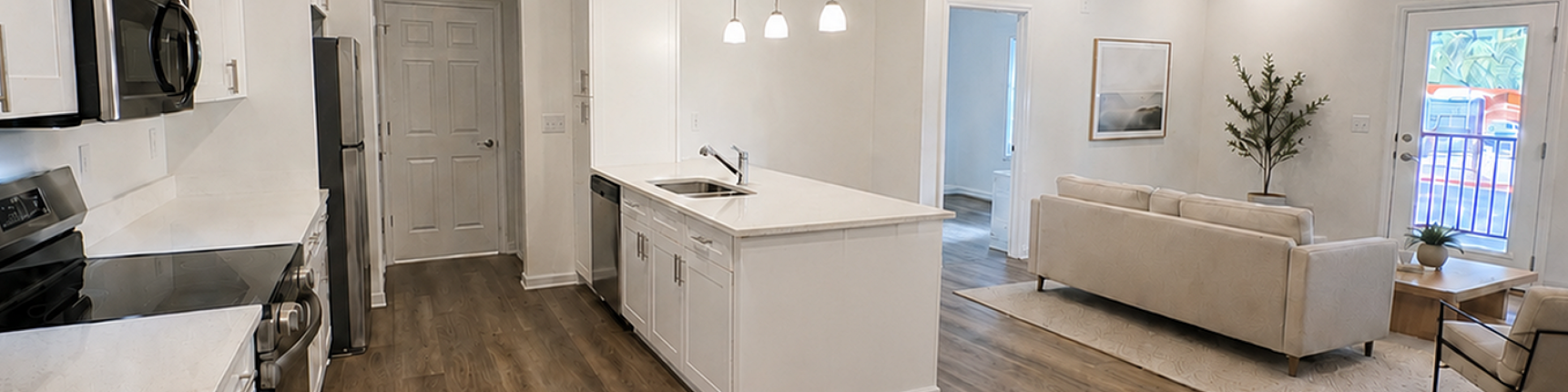 Spacious open-plan apartment featuring a modern kitchen with stainless steel appliances, cozy living room with elegant furnishings, and chic hardwood flooring for ultimate comfort.