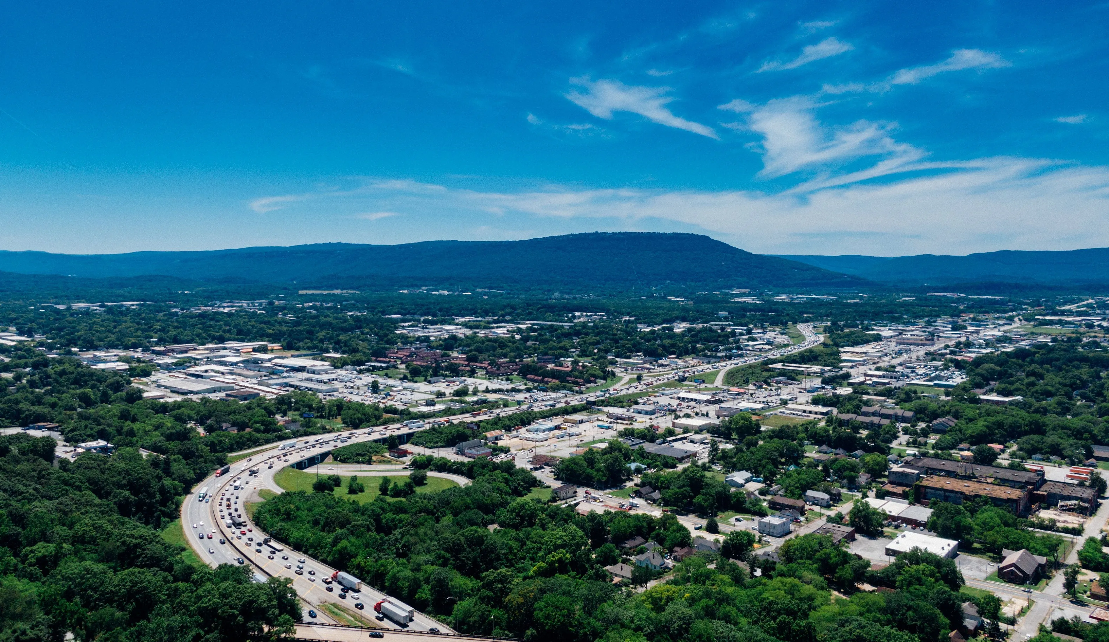 Breathtaking aerial view of a vibrant cityscape with lush greenery and mountains, offering a striking blend of urban and natural beauty.