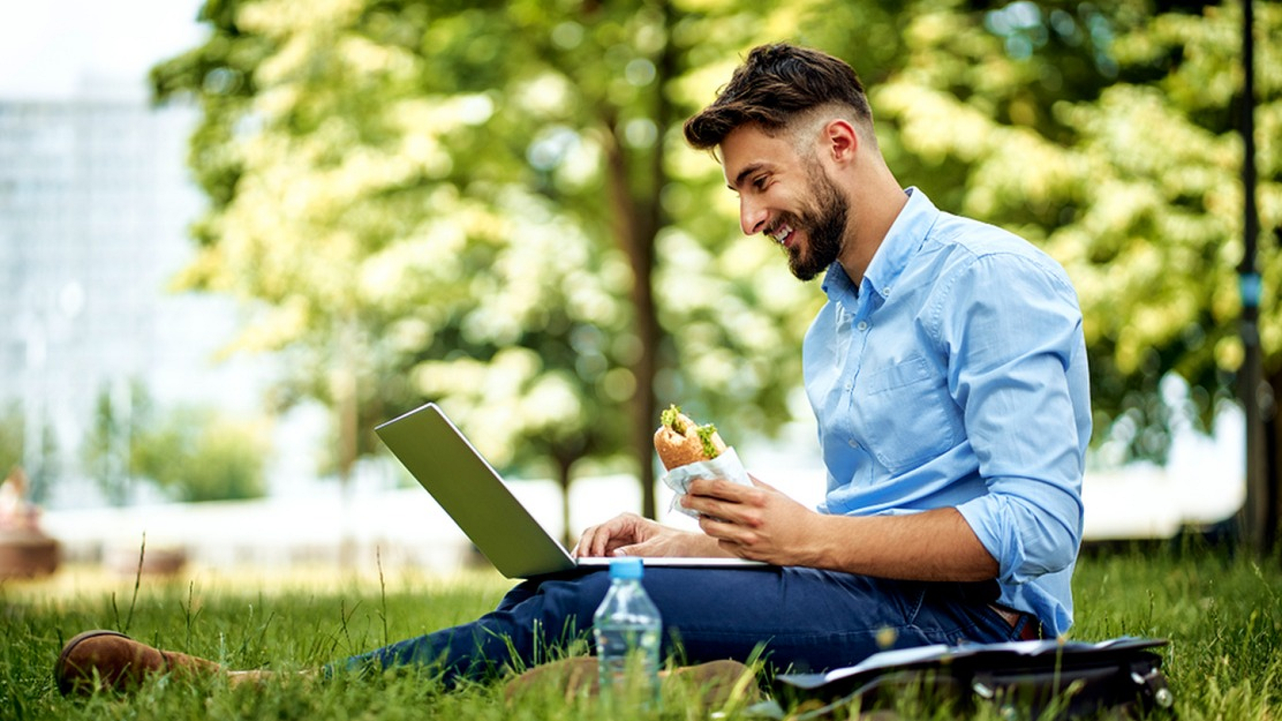 Young professional enjoying an outdoor work session in a serene park setting, combining productivity with relaxation.