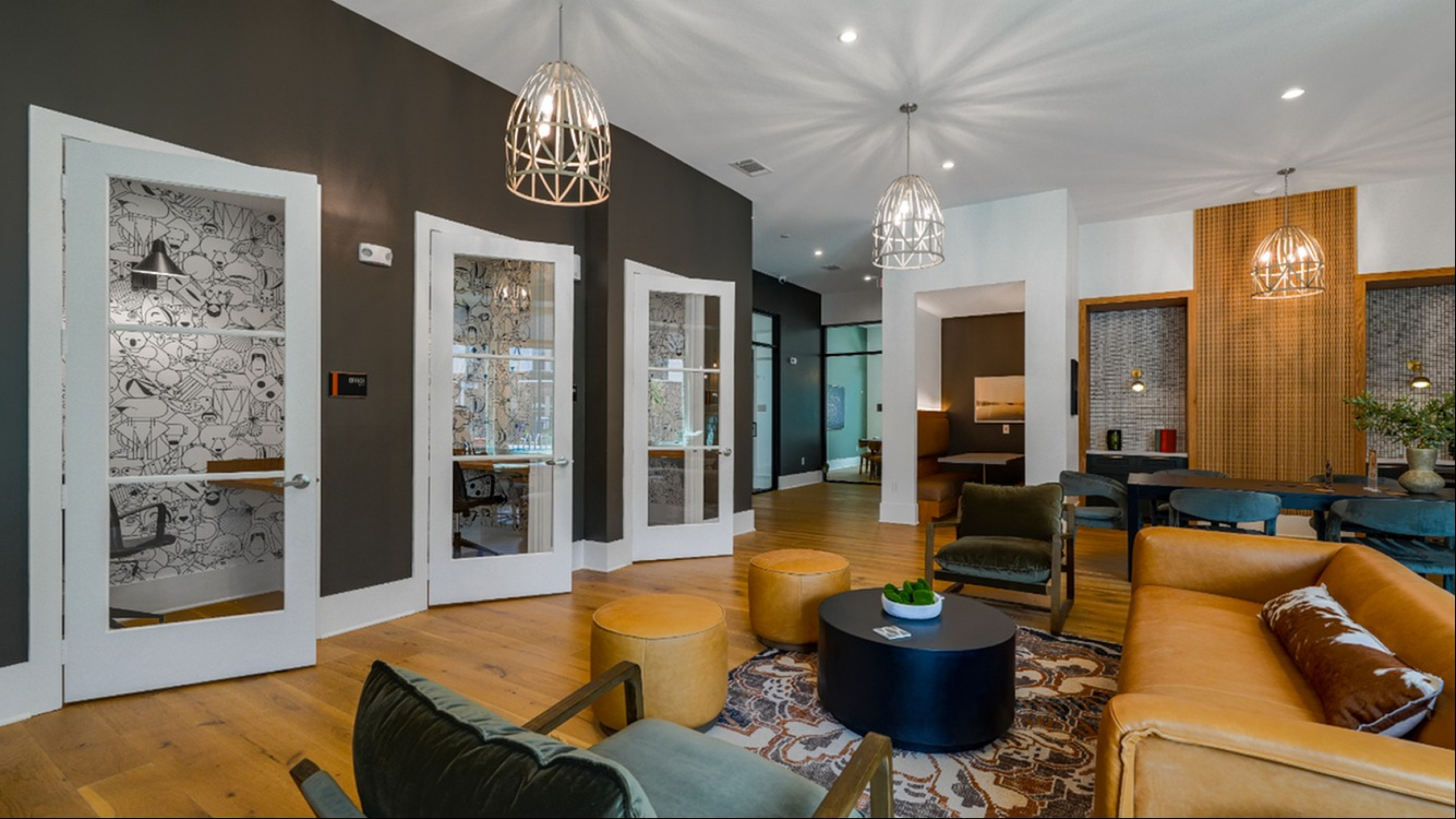 Contemporary apartment lounge featuring stylish pendant lights, a mix of plush seating, and unique wall art decor.