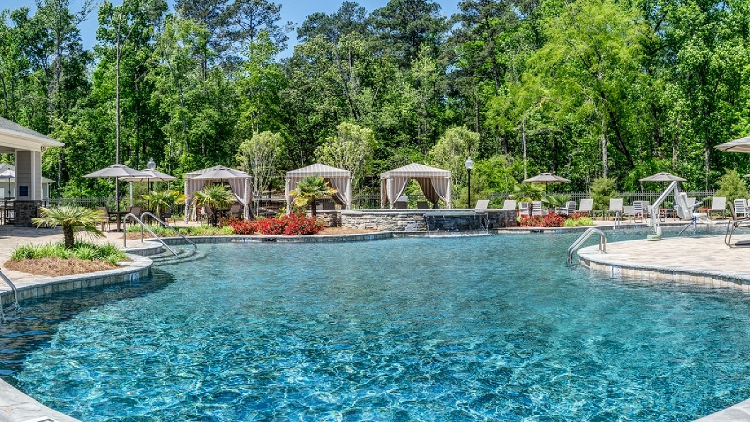 Luxurious resort-style outdoor pool surrounded by lush greenery and stylish cabanas, perfect for relaxation and leisure.