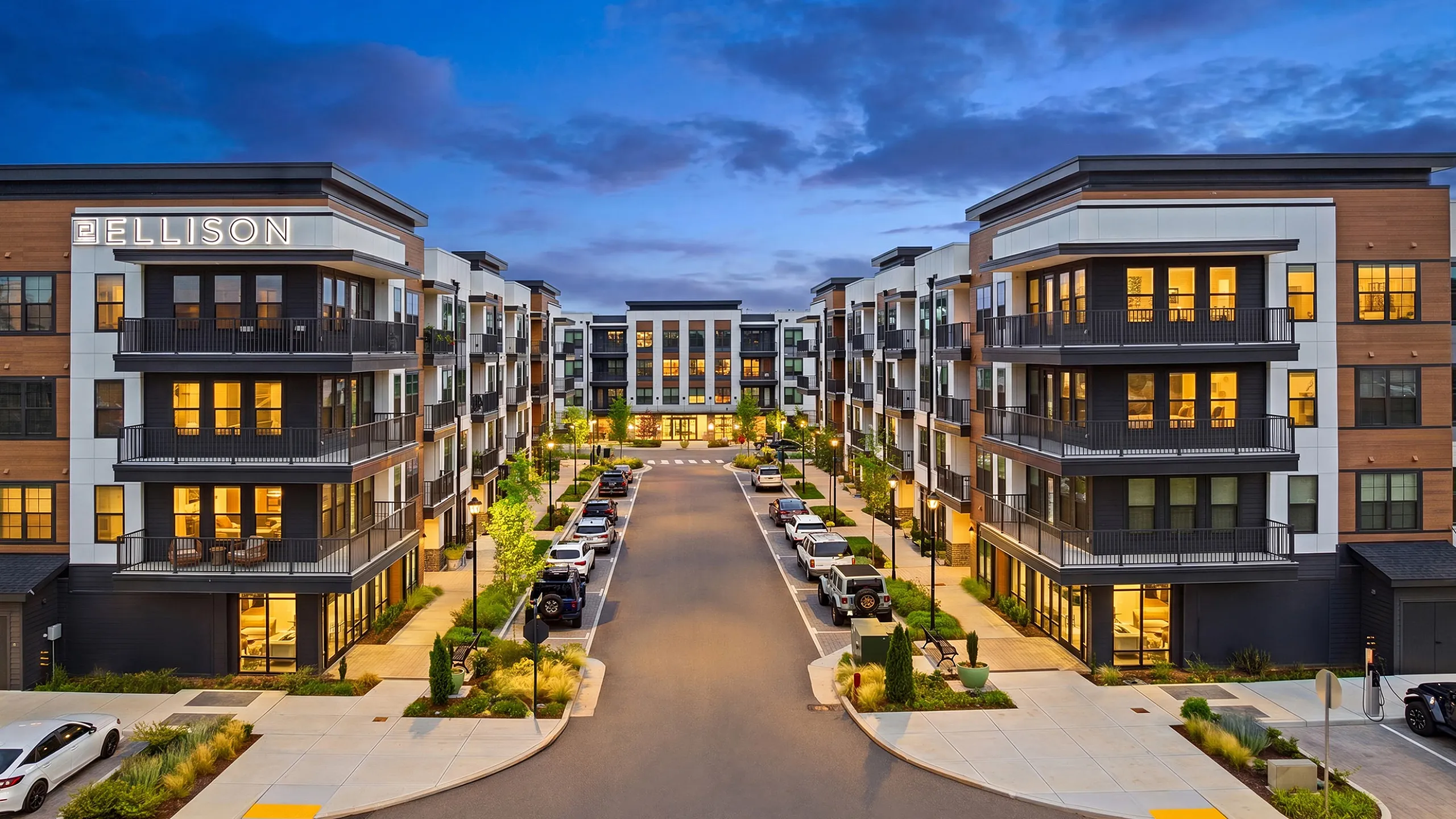 Stunning modern apartment complex with elegant balconies and lush landscaping, illuminated beautifully at twilight.
