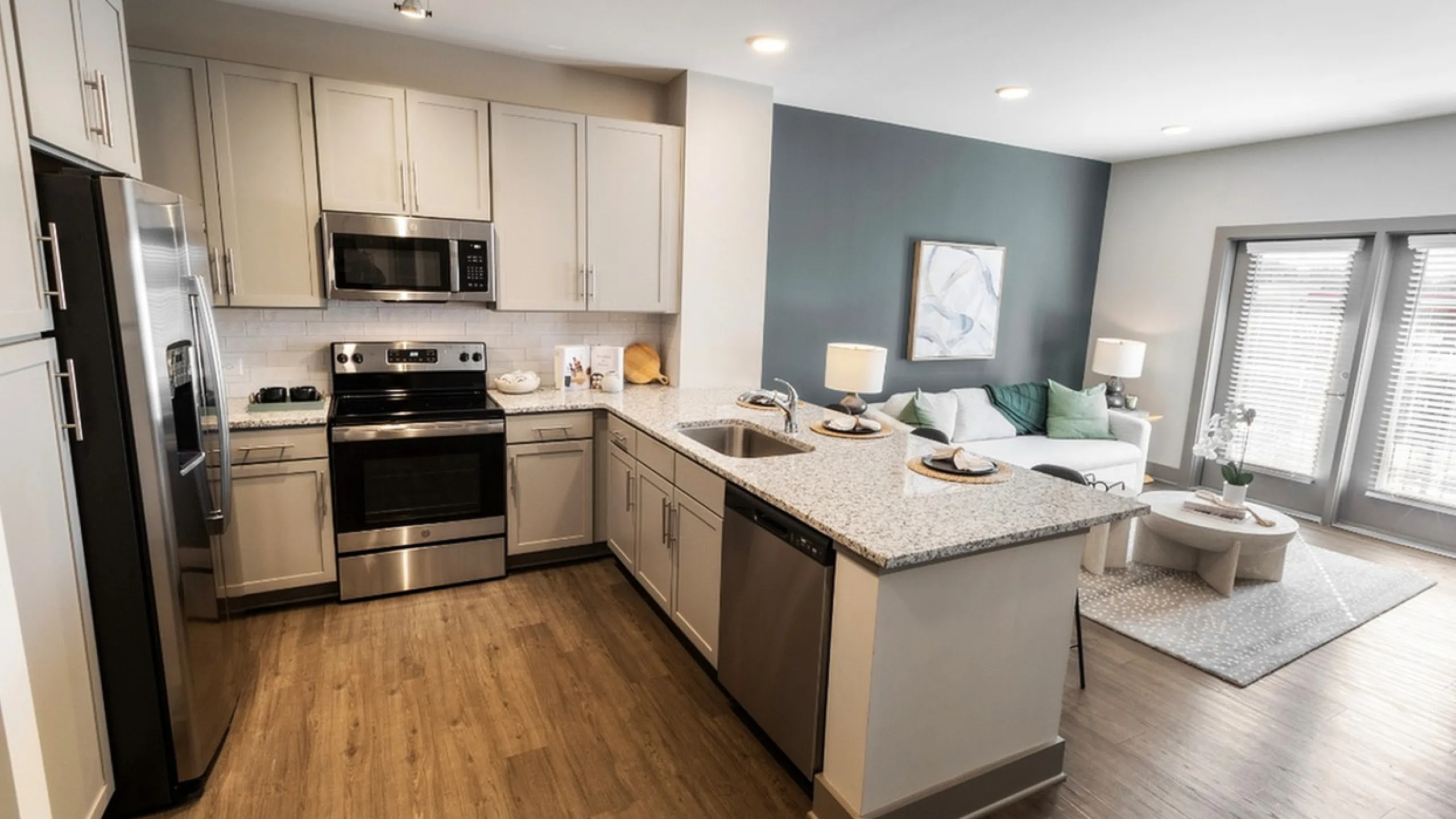 Modern open-concept kitchen and living area featuring sleek appliances, elegant countertops, and cozy seating under warm lighting.