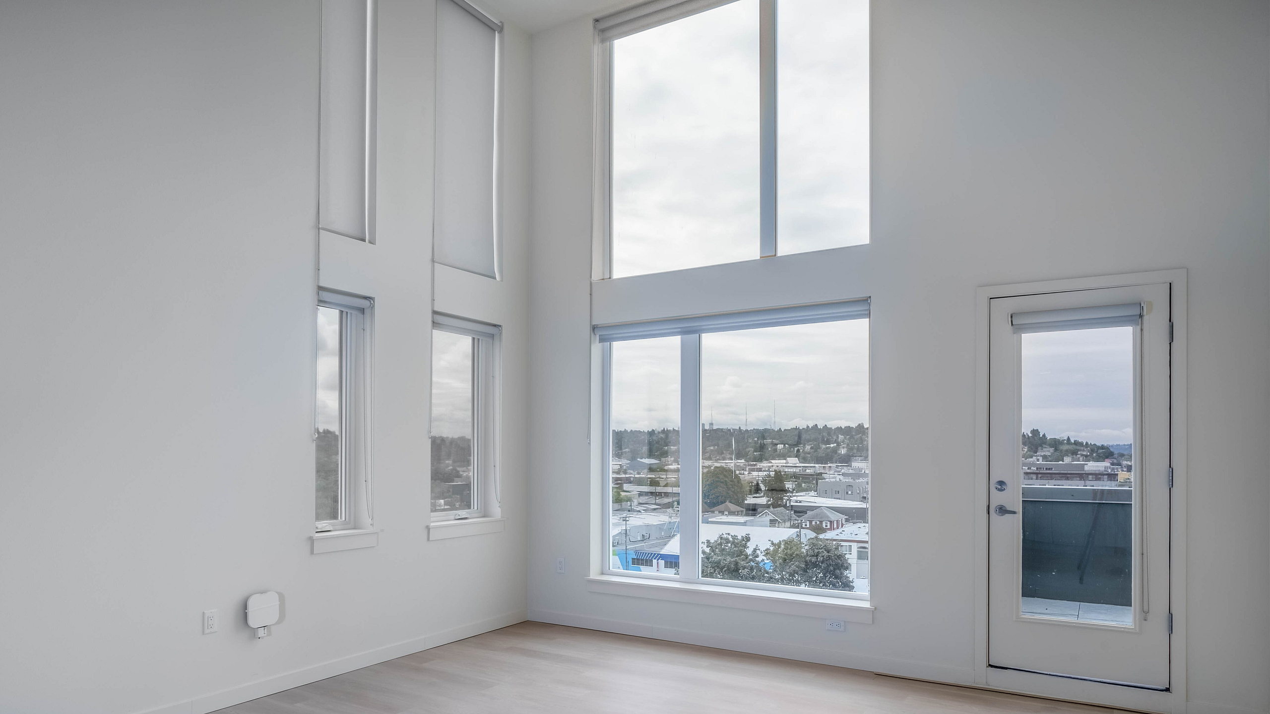 Bright and airy room with floor-to-ceiling windows offering stunning city views, perfect for a modern and elegant living space.