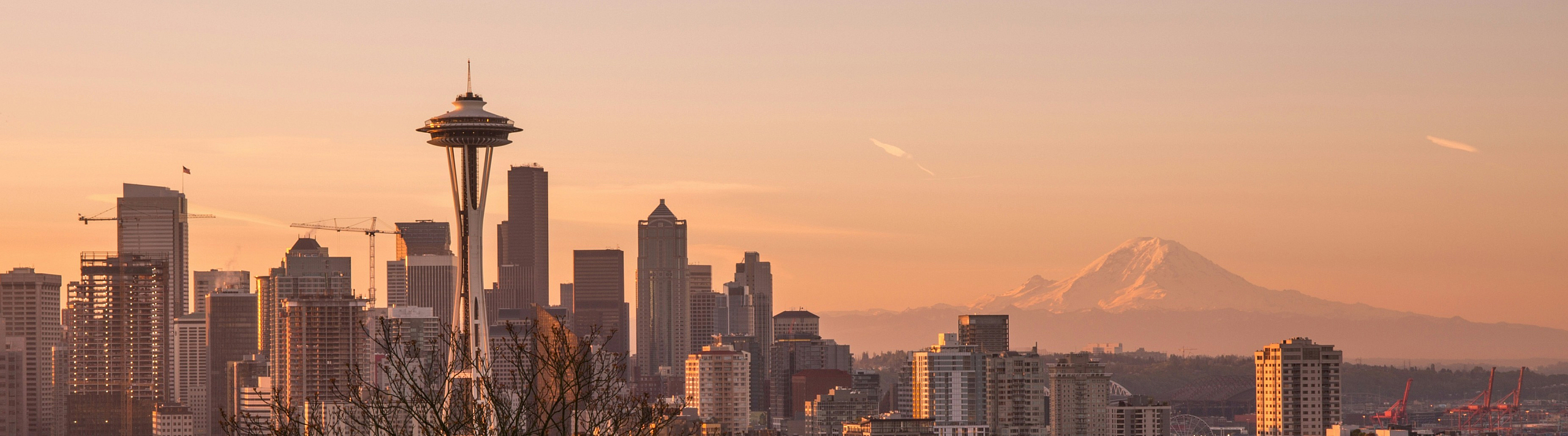 Stunning Seattle skyline at sunset with iconic Space Needle and majestic Mount Rainier in the background.