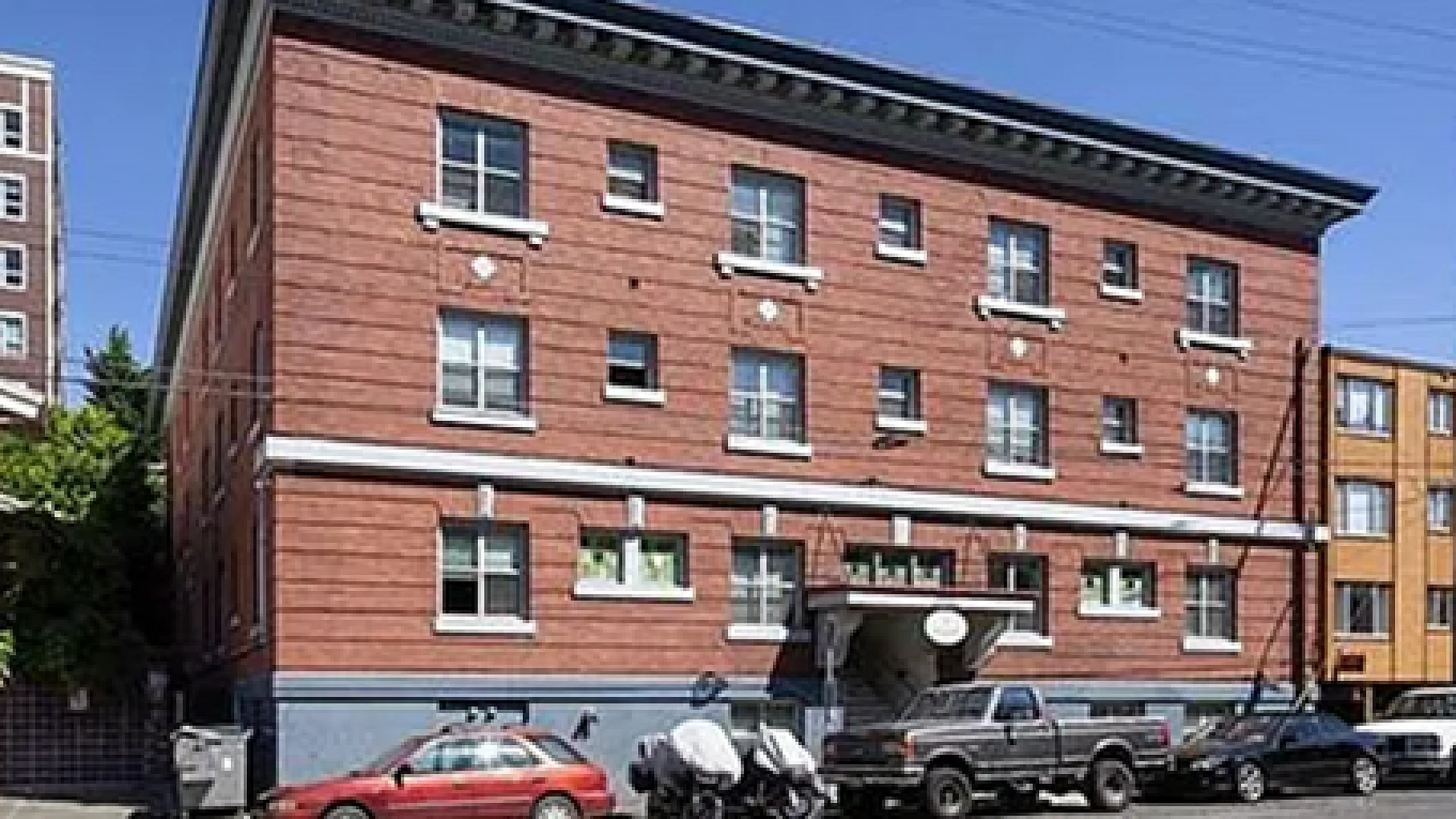 Charming red brick apartment building with historic architecture, featuring large windows and convenient parking in a vibrant neighborhood.