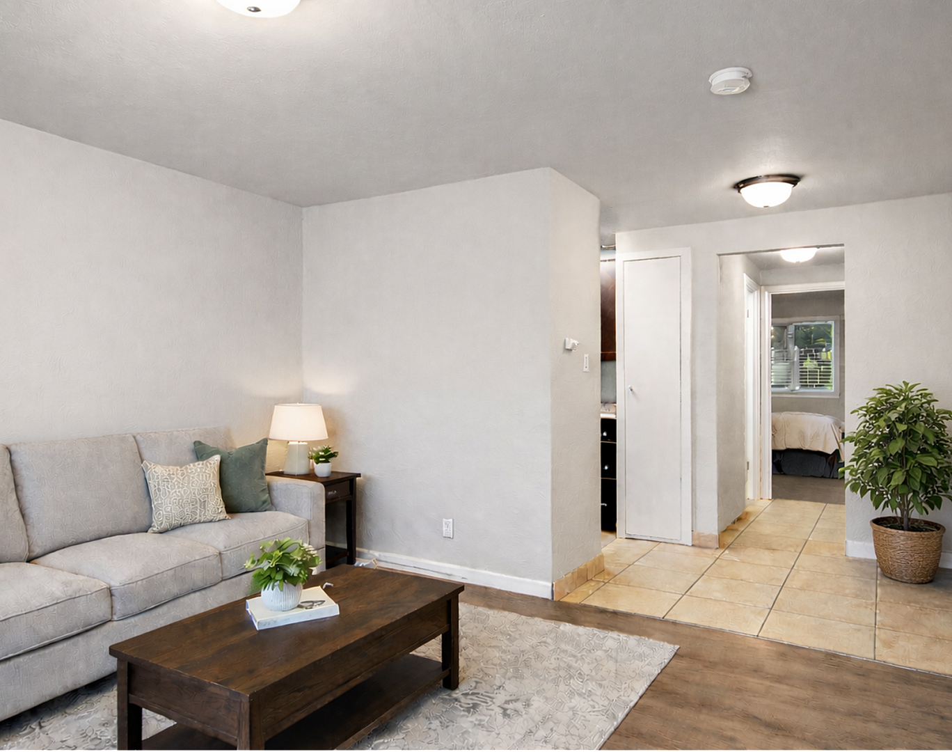 Inviting living space with cozy seating, elegant decor, and a glimpse of a bright bedroom through the hallway.