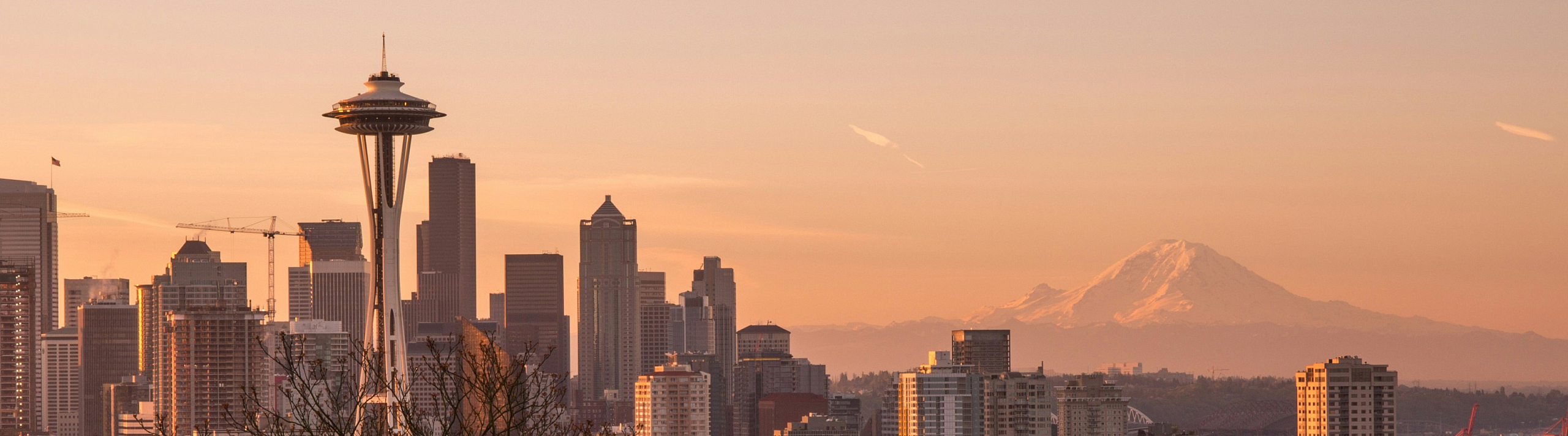 Breathtaking cityscape of Seattle with the iconic Space Needle and majestic Mount Rainier at sunset, perfect urban living backdrop.