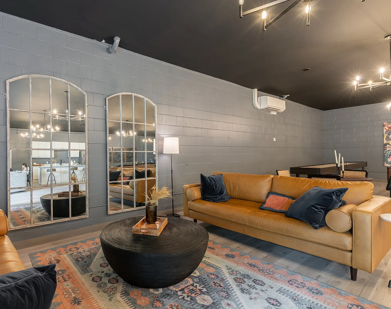 Chic modern living space with warm leather sofas, elegant lighting, and mirrored accents.
