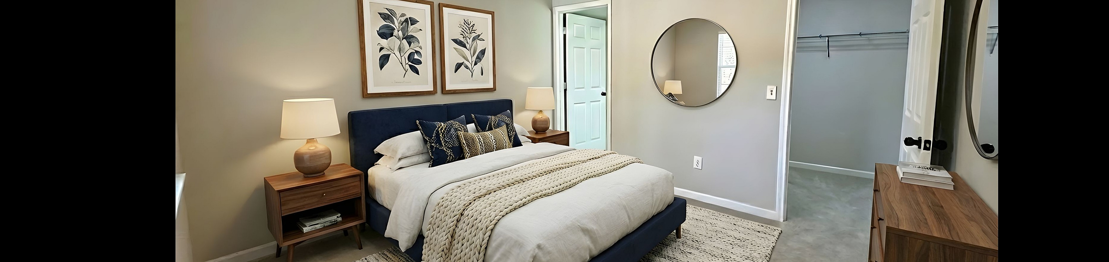 Elegant bedroom with modern decor featuring a plush blue bed, stylish artwork, wooden furniture, and a spacious walk-in closet.