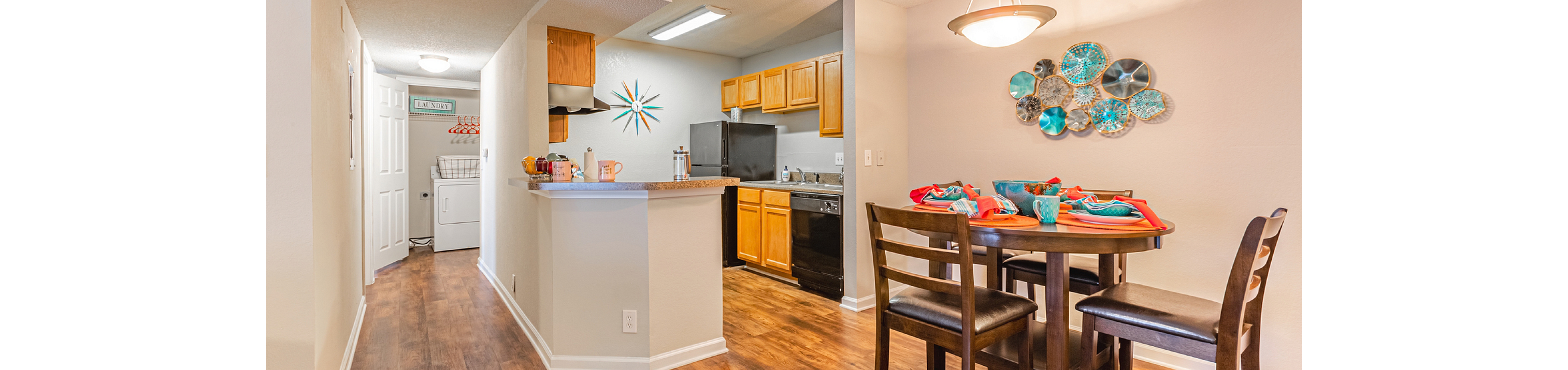Charming open-concept dining and kitchen area with elegant wooden floors, modern light fixtures, and vibrant wall decor.
